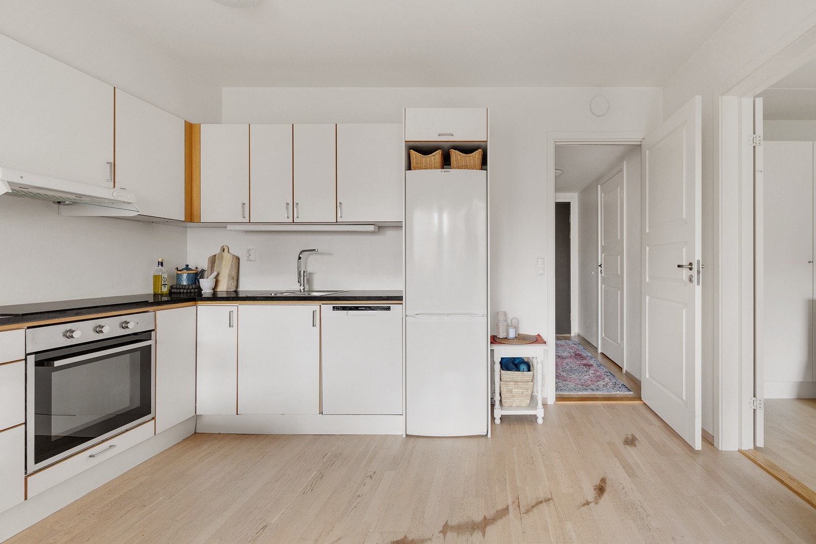 Kjøkkenet har en moderne innredning med hvite glatte fronter og en benkeplate av laminat. Galleribilde