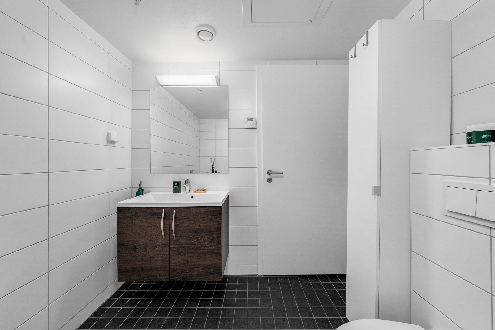 Pent fliselagt bad fra byggeår, 2018. Badet er med lyse fliser på vegger og mørke fliser på gulv. Galleribilde