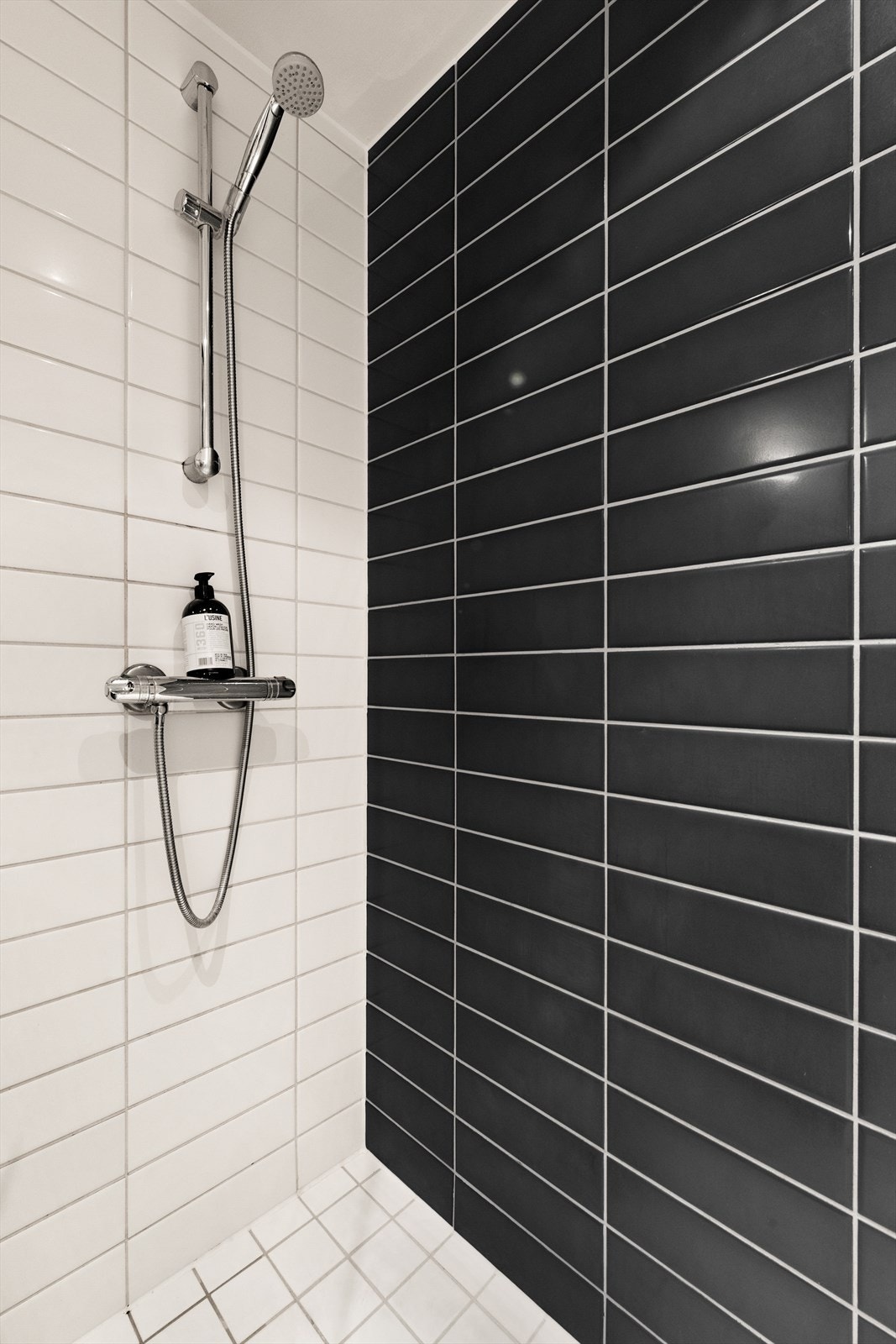 Baderommet er funksjonelt og stilrent, med fliser på gulv og vegger samt varmekabler som gir god komfort. Det er utstyrt med servant på underskap, et speil med belysning, gulvstående toalett, og en dusj med glassvegger. Galleribilde