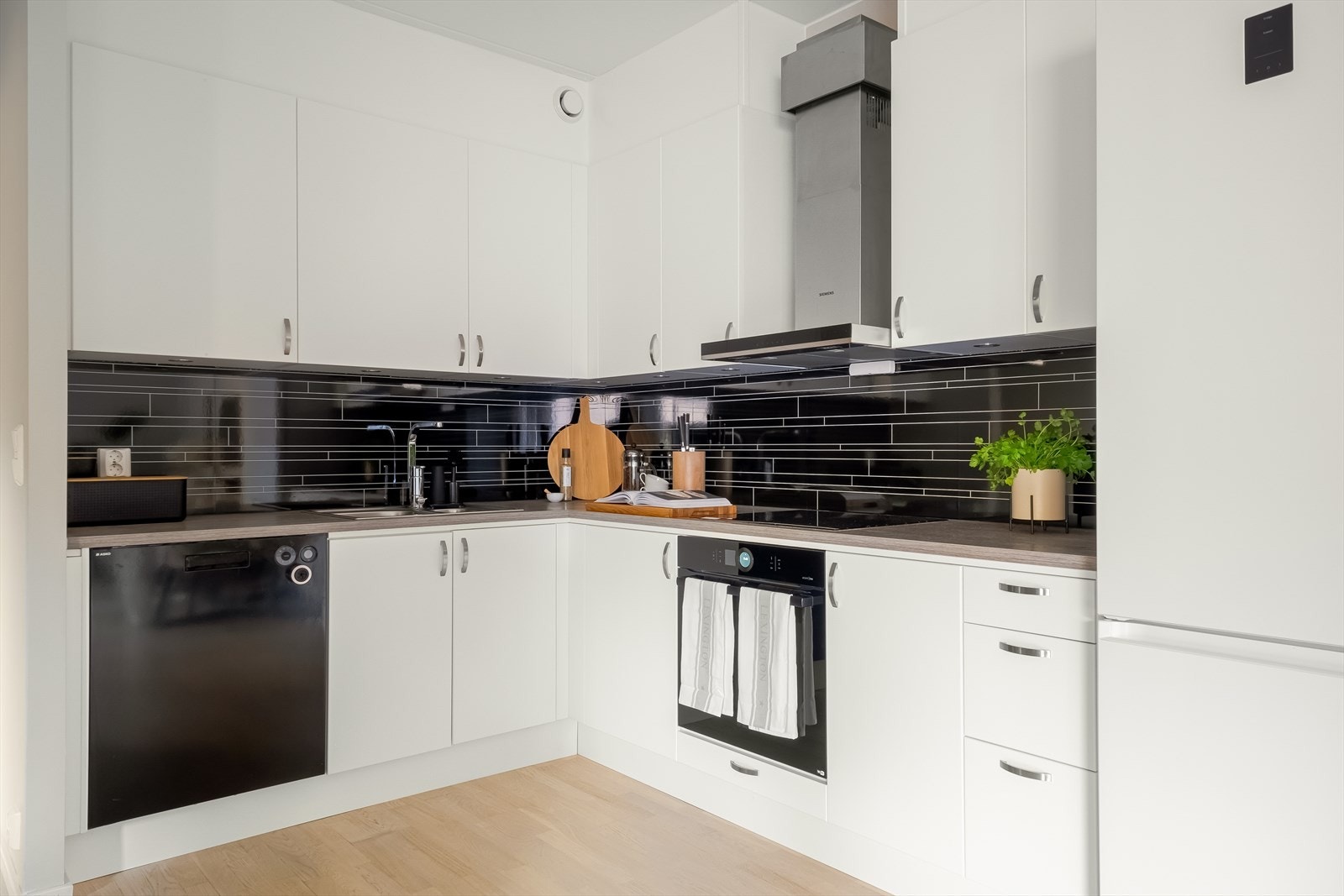 Innredning med hvite glatte, folierte fronter. Laminat benkeplate med nedfelt kum i rustfritt stål. Flislignende plater på vegg over benk. Downlights (led) under overskap. Galleribilde