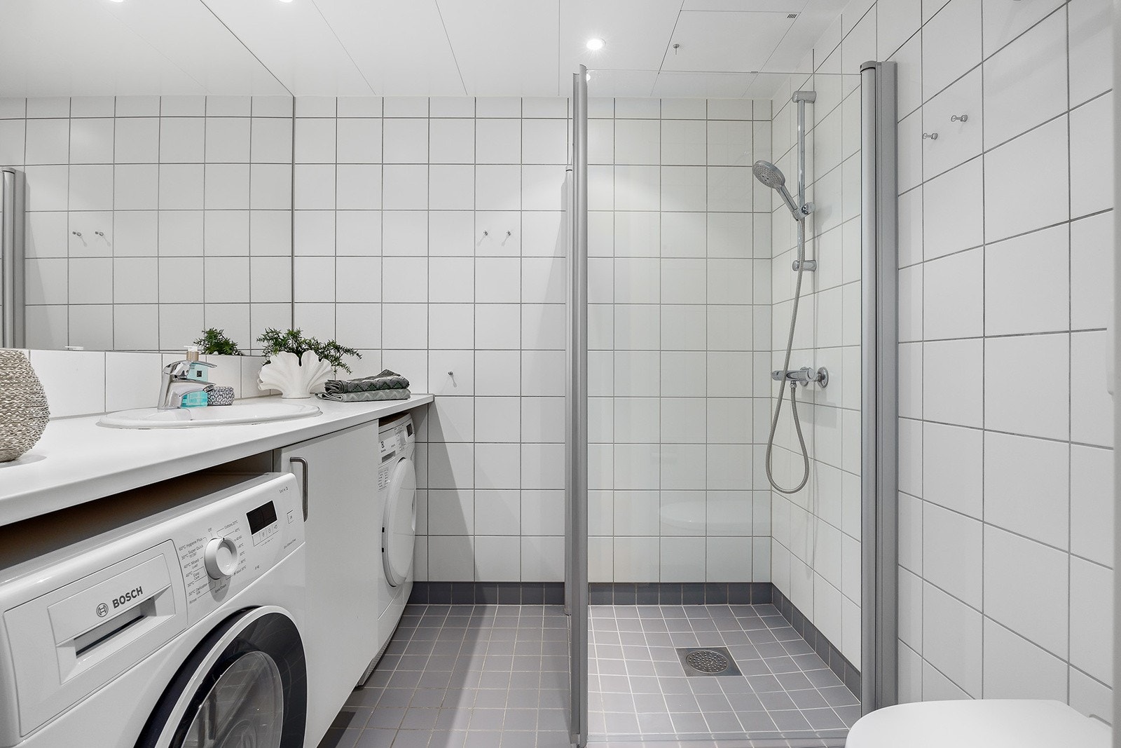 Delikat helfliset bad fra 2012 med gulvvarme og downlights i himlig, dusjhjørne, stort speil over servan, vegghengt toalett og opplegg til vaskemaskin og tørketrommel Galleribilde