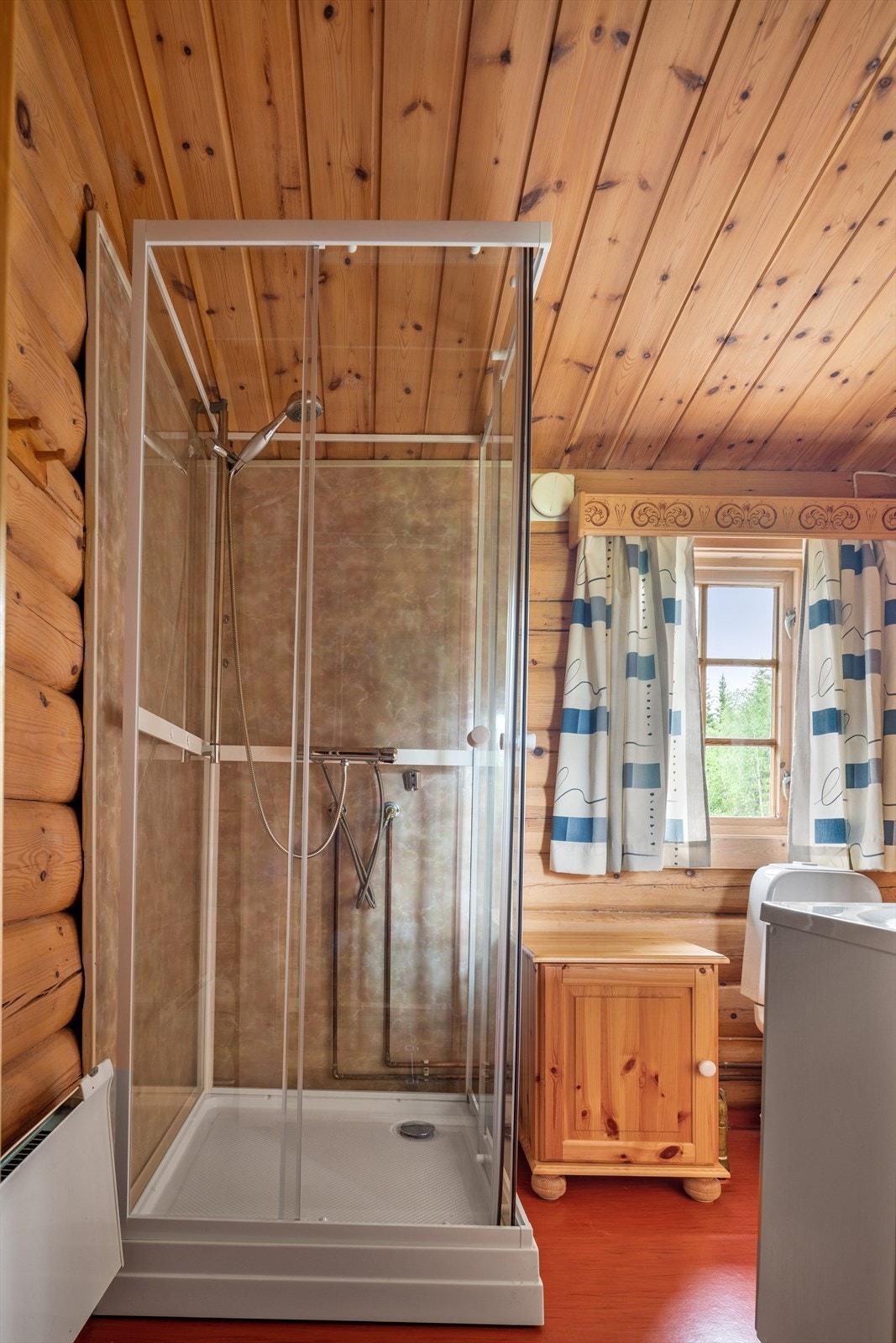 Baderommet er innredet med servant i skapinnredning, høyskap, dusjkabinett og gulvmontert toalett. Panelovn montert på vegg som varmekilde. Galleribilde