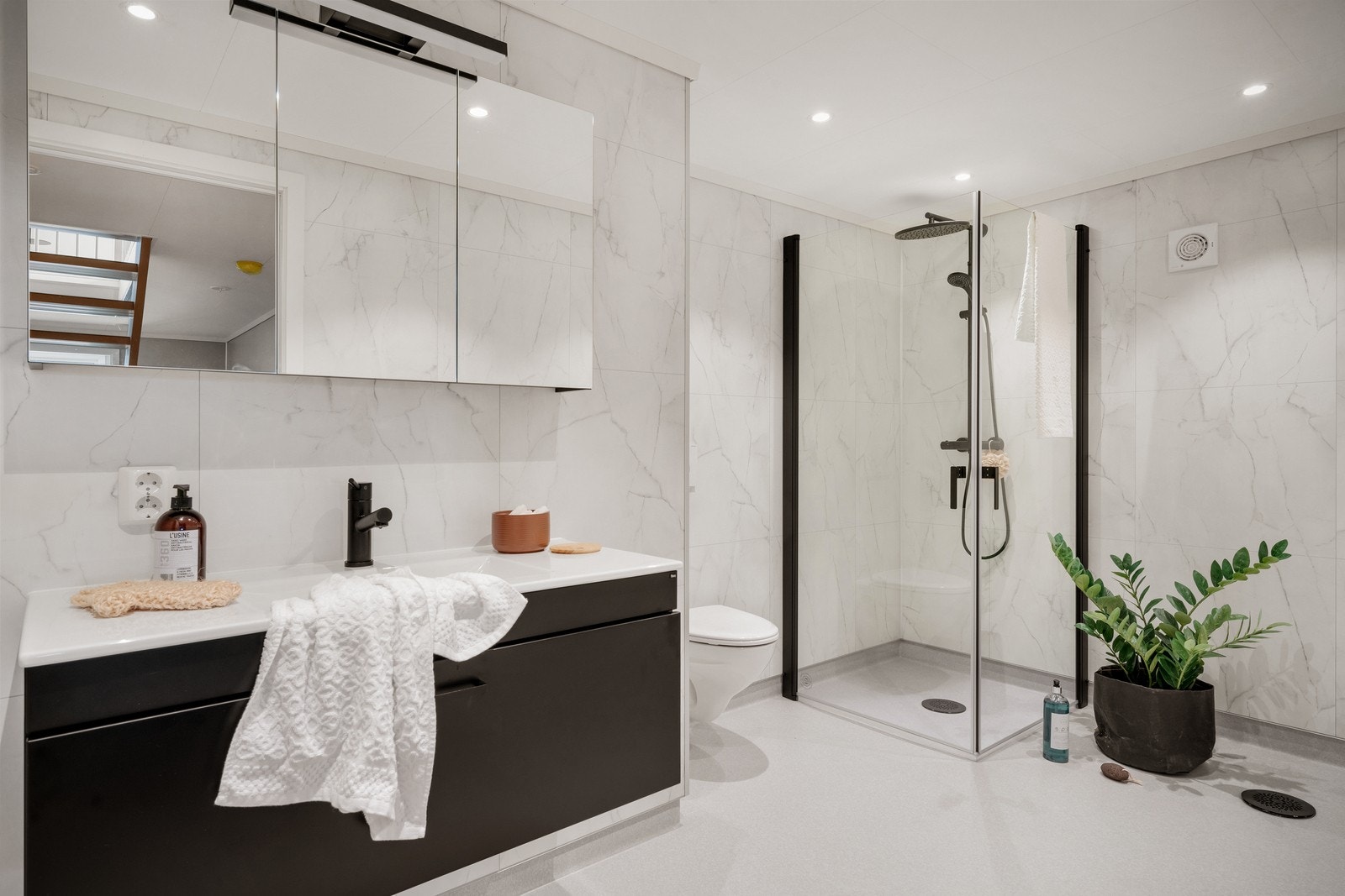 Badet nede: Her er det lyse baderomsplater med marmormønster som passer perfekt til de sorte detaljene på kraner, møbler og dusjhjørnet. Galleribilde