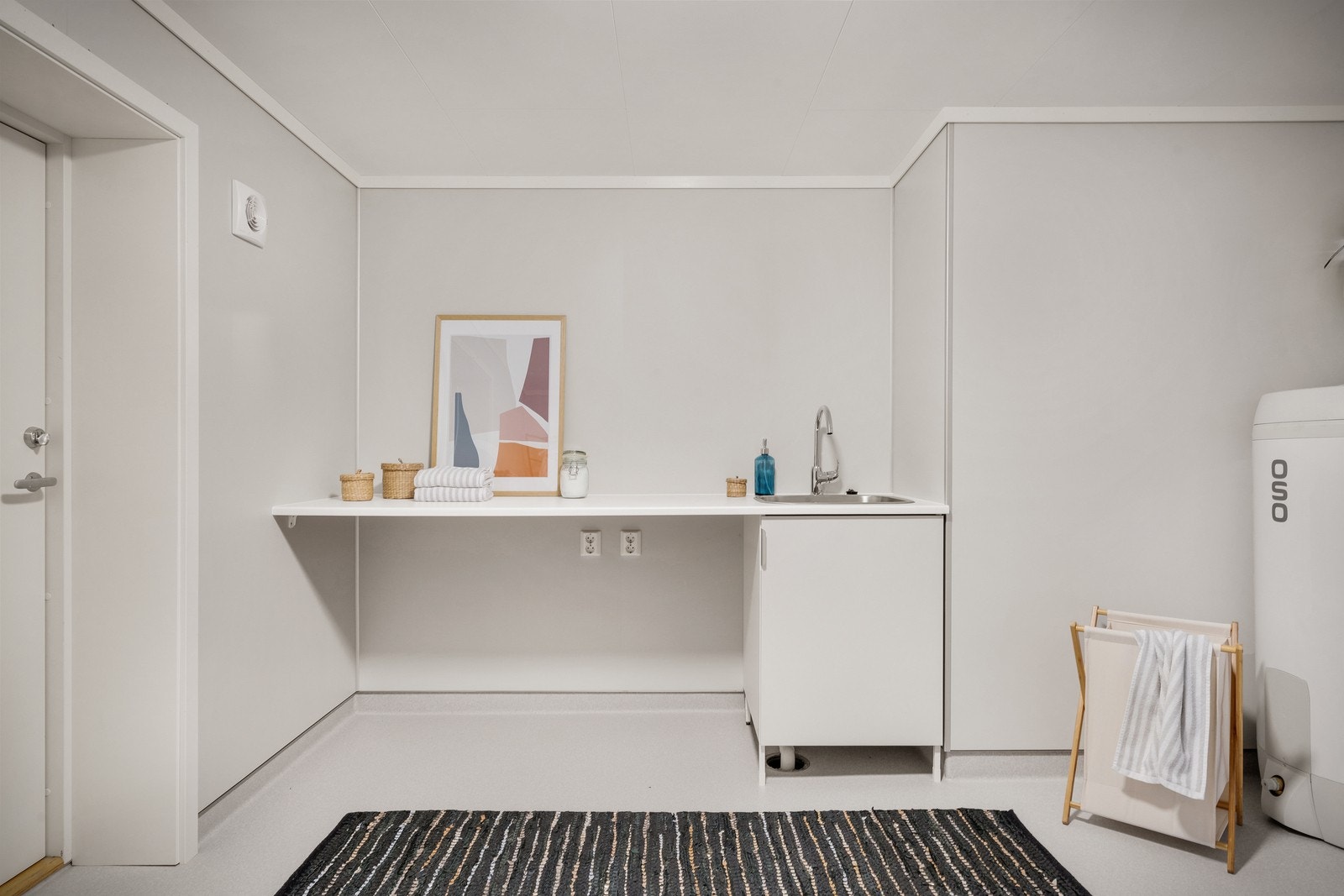 Vaskerommet er innredet med benk for vaskemaskin, tørketrommel og utslagsvask. Galleribilde