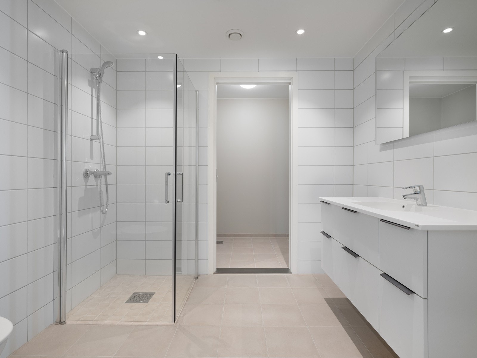 Badet er helfliset og har gulvvarme. Innredningen består av en heldekkende servant på skuffeseksjon og speil. Galleribilde