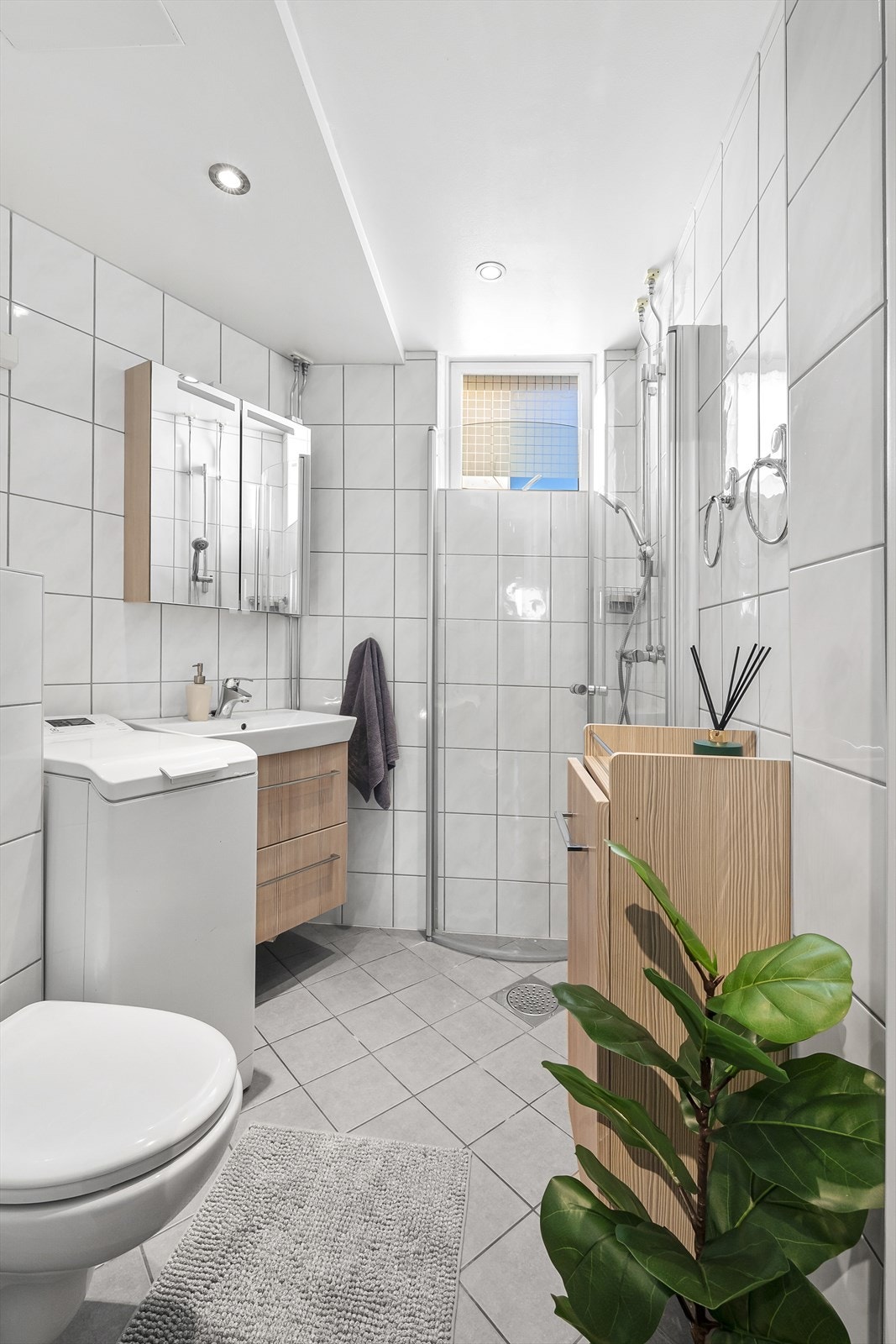 Innredning i badet består av servantskap, speil, dusjhjørne med glassdører og toalett. Galleribilde