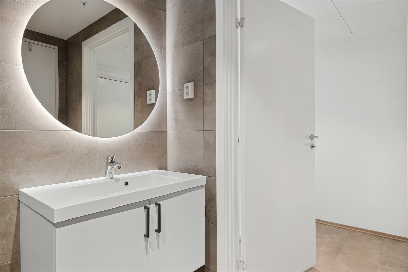 Fra gangen har man direkte adkomst til baderommet, med flere flotte detaljer. Over baderomsinnredningen pryder et belysningsspeil på 80cm diameter. Det er gjort tilvalg på innredning med håndtak i grå epoxi. Galleribilde