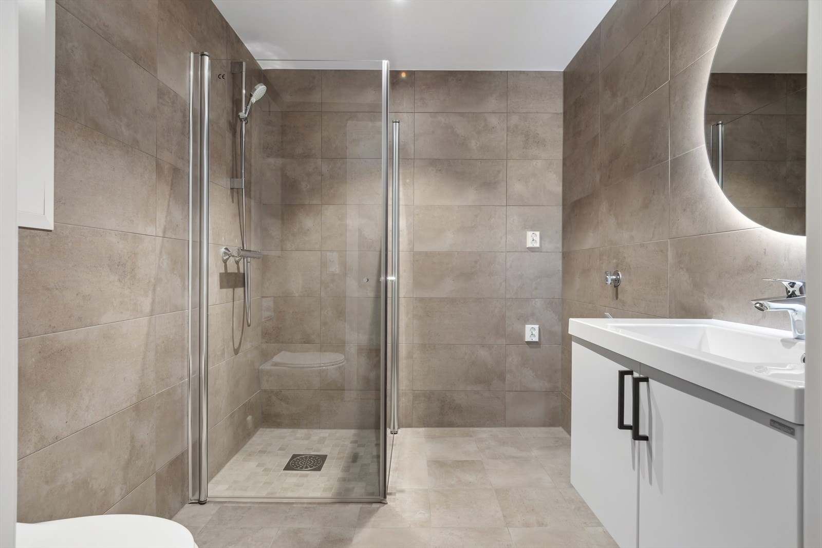 Baderommet byr på en rekke gode kvaliteter med blant annet innfellbare dusjdører, vegghengt toalett og opplegg for vaskemaskin. Det er naturligvis også gulvvarme. Galleribilde