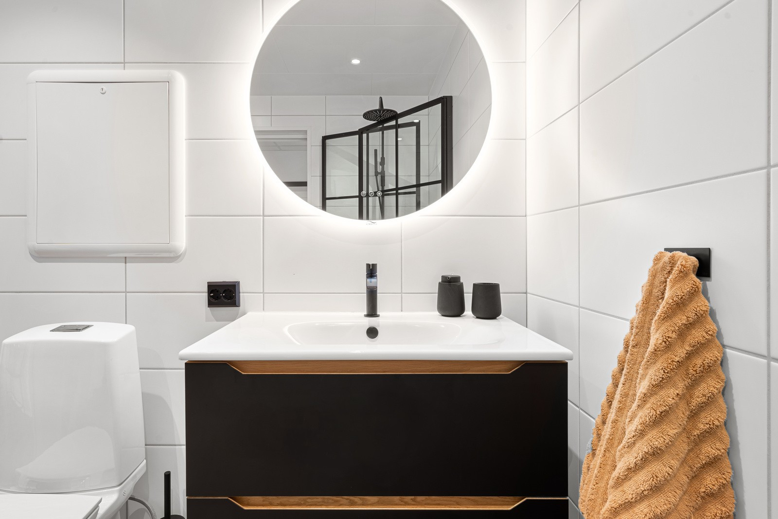 Badet fremstår moderne med lekker baderomsinnredning og overspeil med belysning.