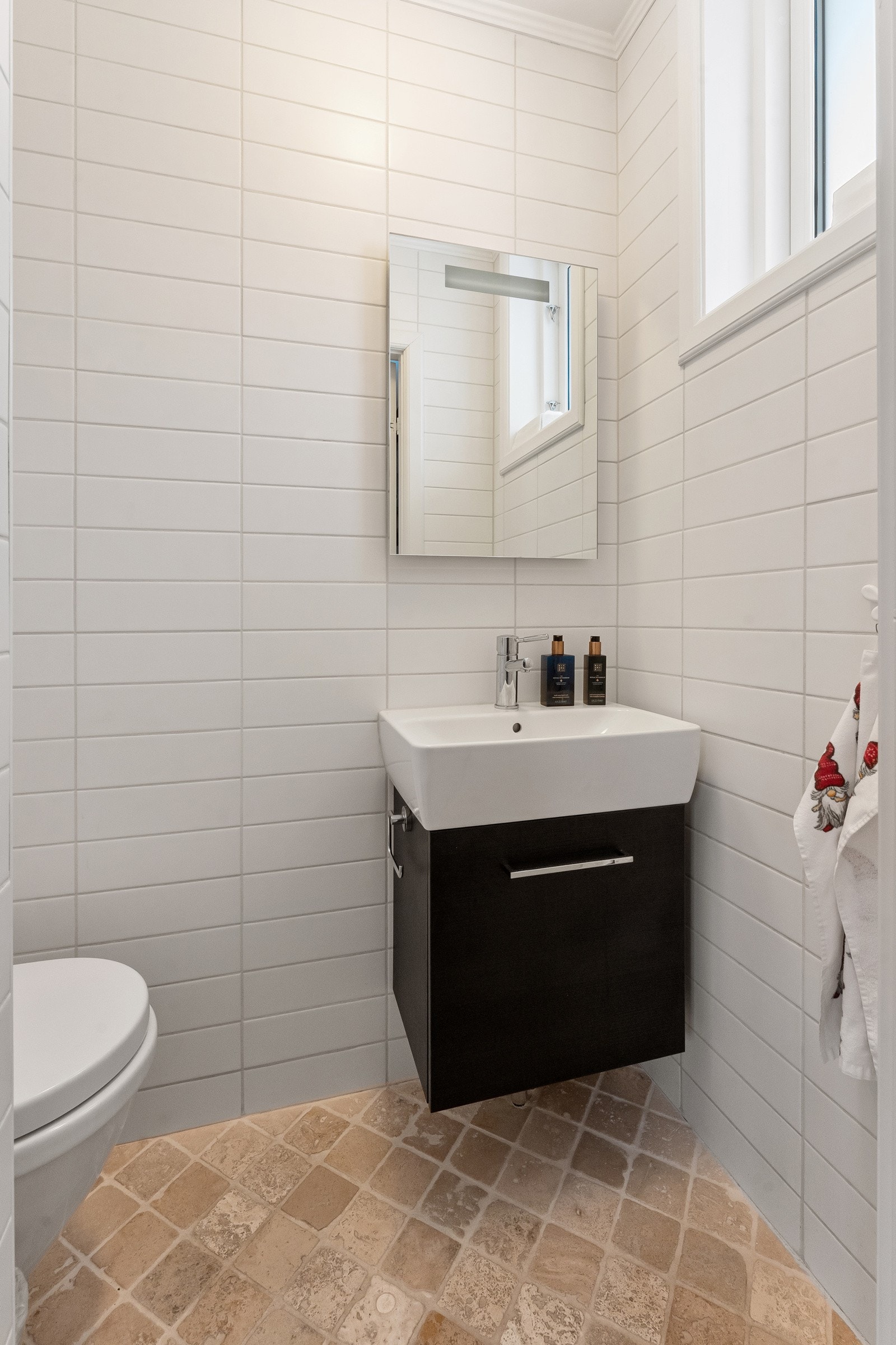 Wc-rommet har vegghengt toalett, et sort servantskap og et lite speil med integrert belysning. Galleribilde