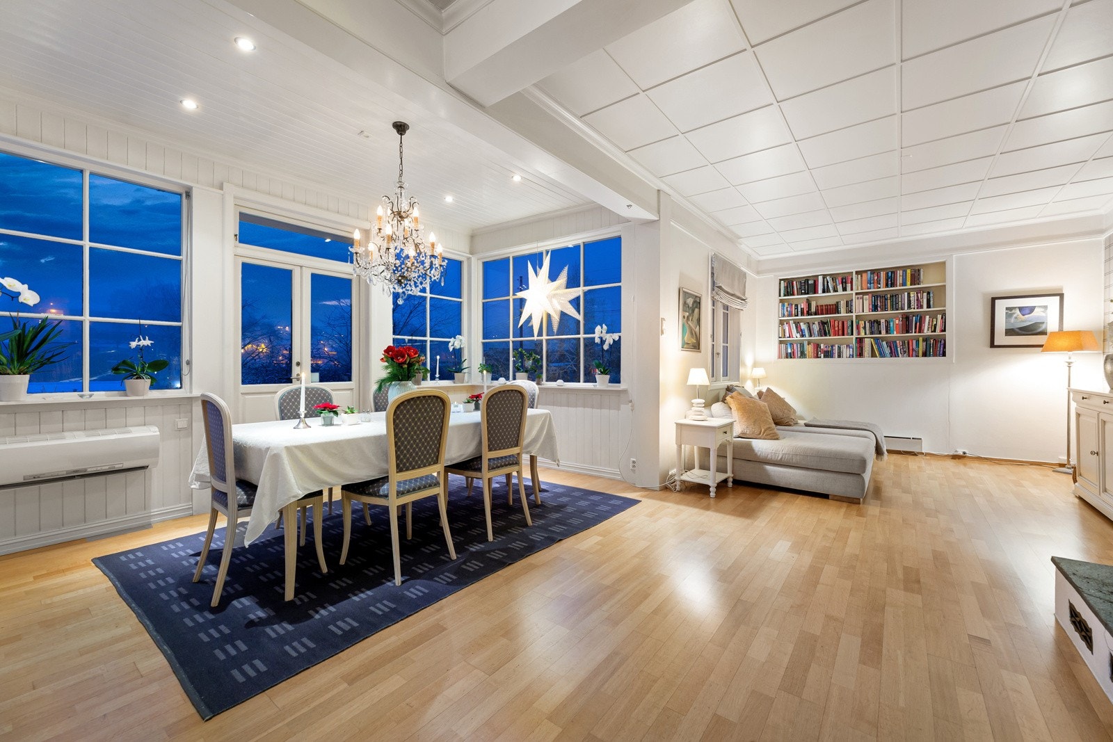 Deler av stuen ligger i en vinterhage med vinduer på tre sider, og her er det plass til å samle venner og familie rundt et langbord Galleribilde