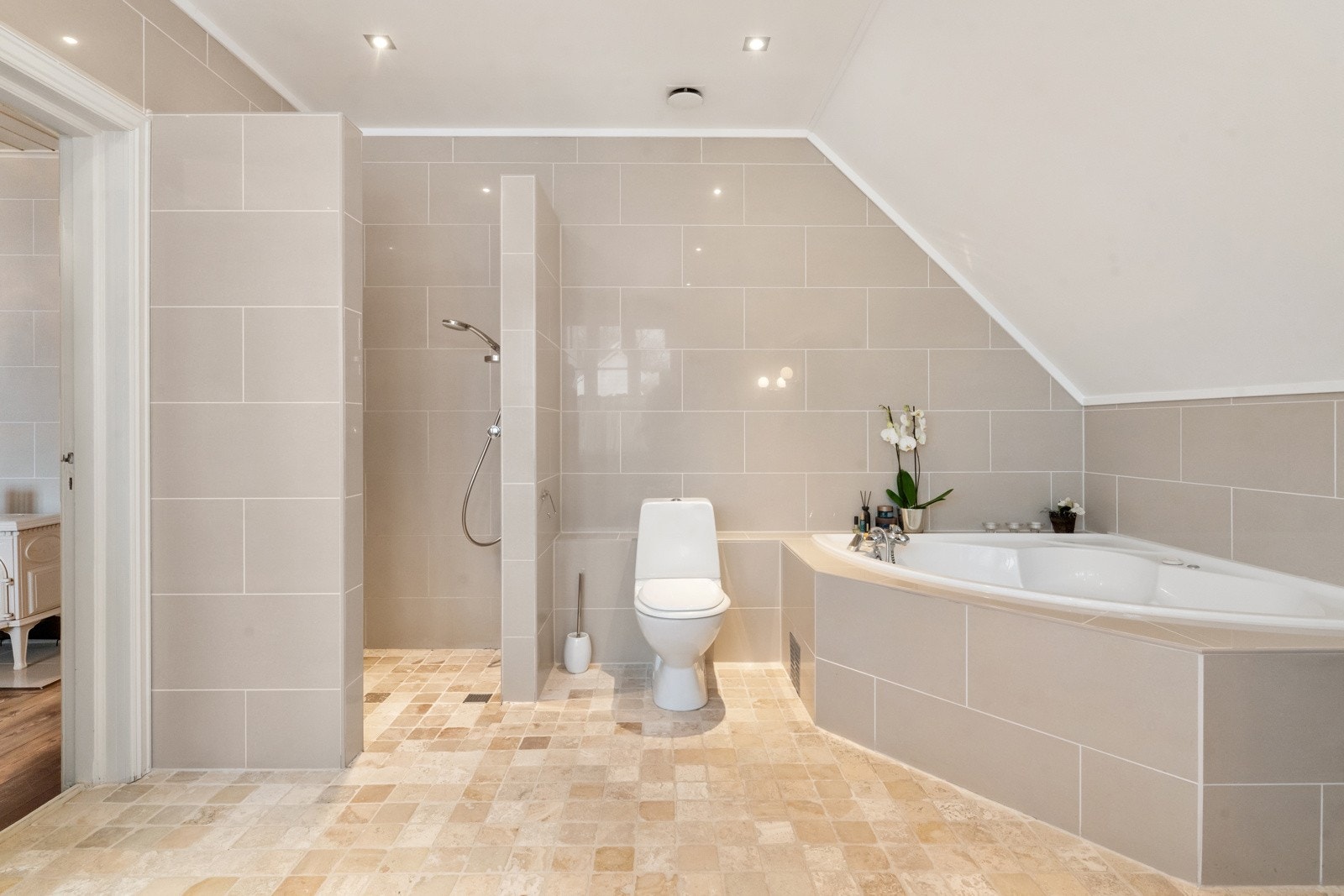 Et av boligens to bad ligger i suiteløsning med hovedsoverommet. Badet har bl.a. nedsenket dusjnisje og et flott hjørnebadekar med dusjløsning. Galleribilde