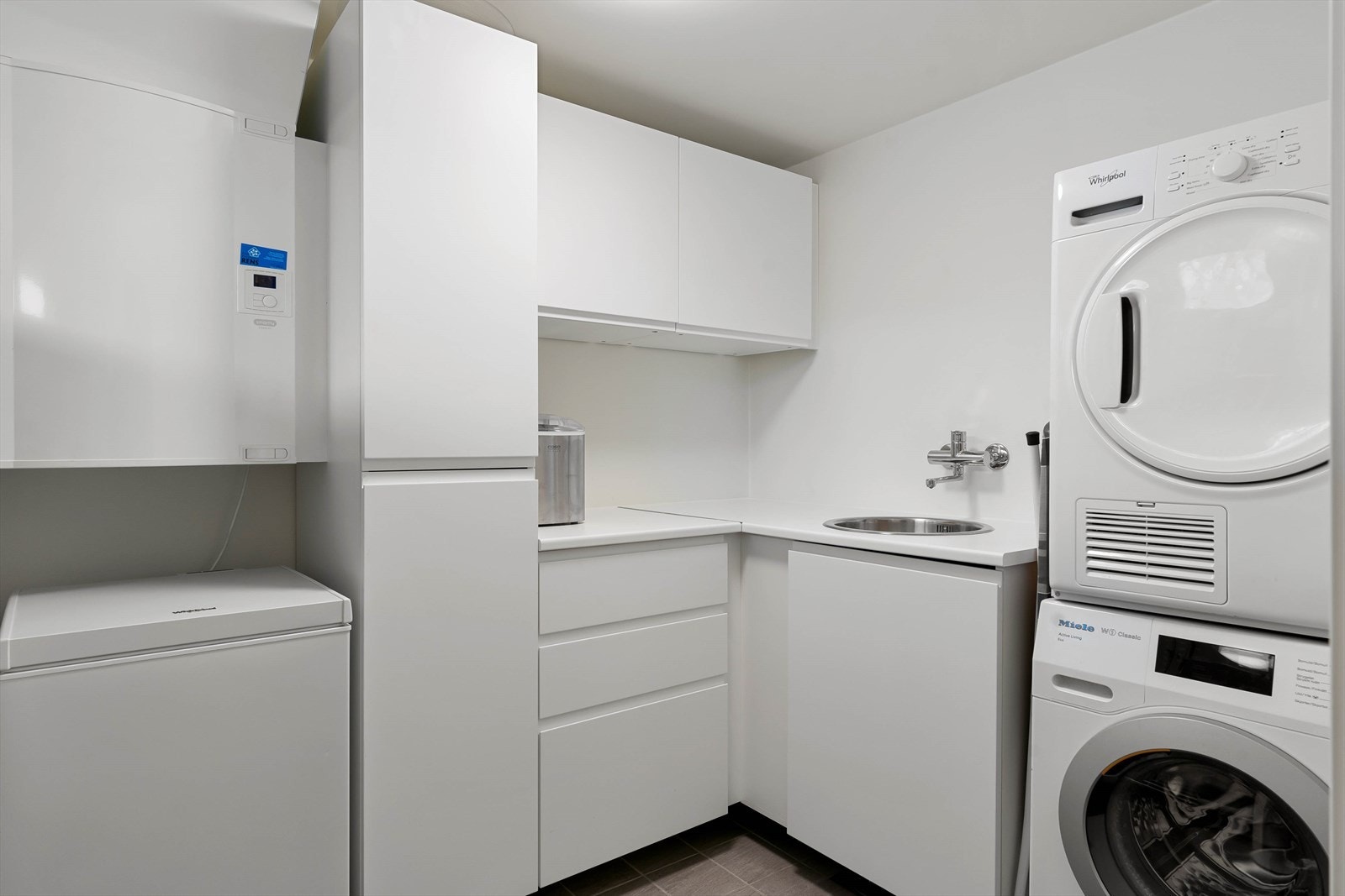 Praktisk vaskerom med oppbevaringsmuligheter og benkeplate med utslagsvask. Galleribilde