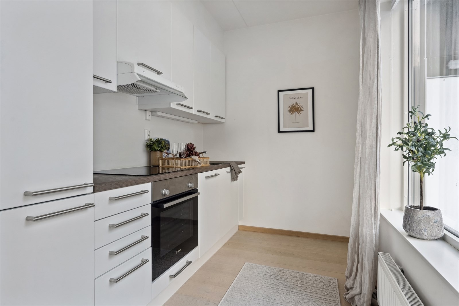 Kjøkkeninnredningen er tidsløs og lekker med hvite, glatte frnter og benkeplate i laminat. Galleribilde