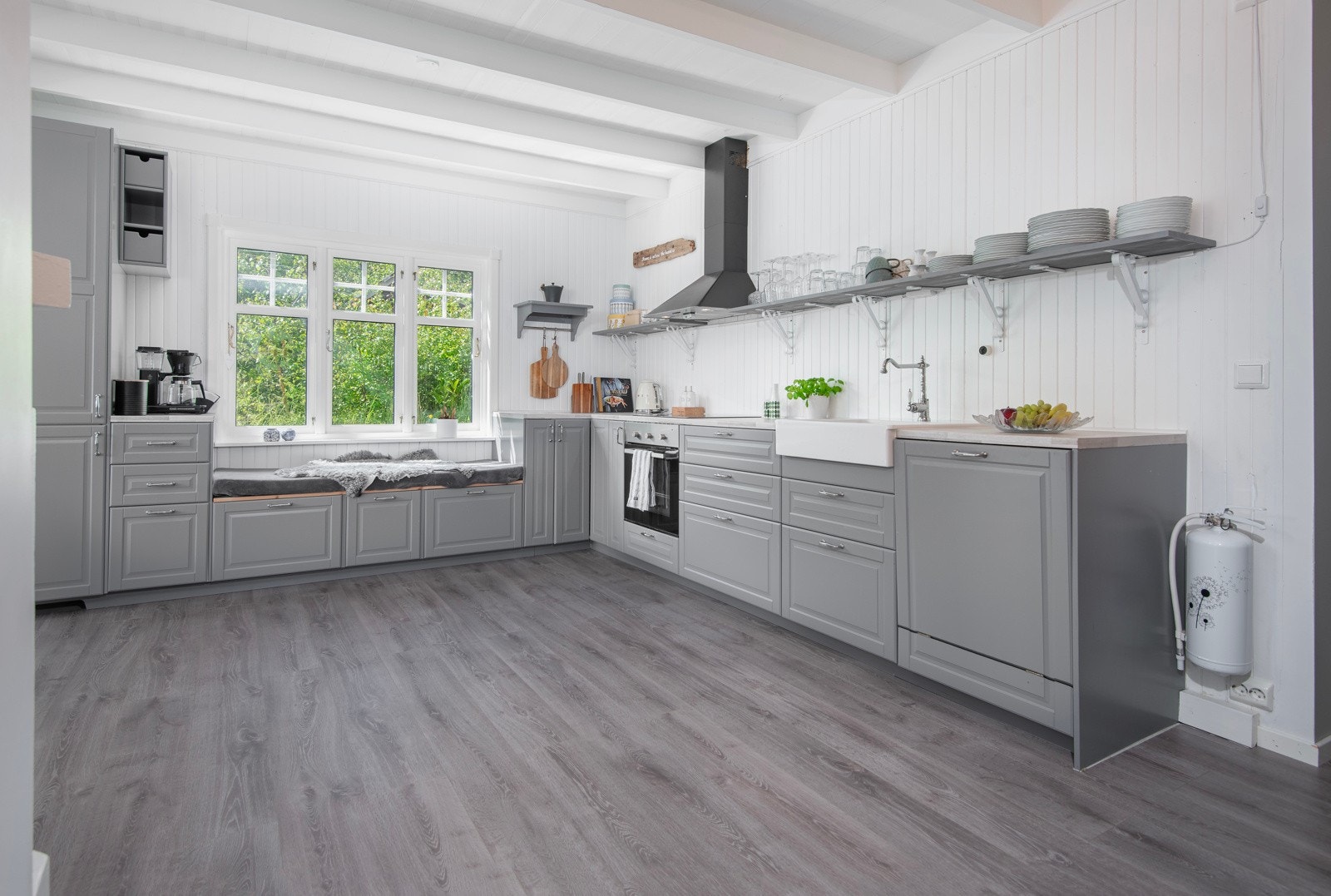 Innredningen fra Ikea har grå profilerte fronter og laminat benkeplate. Det er godt med skap- og skuffeplass, samt en koselig slagbenk med skuffer under. Galleribilde