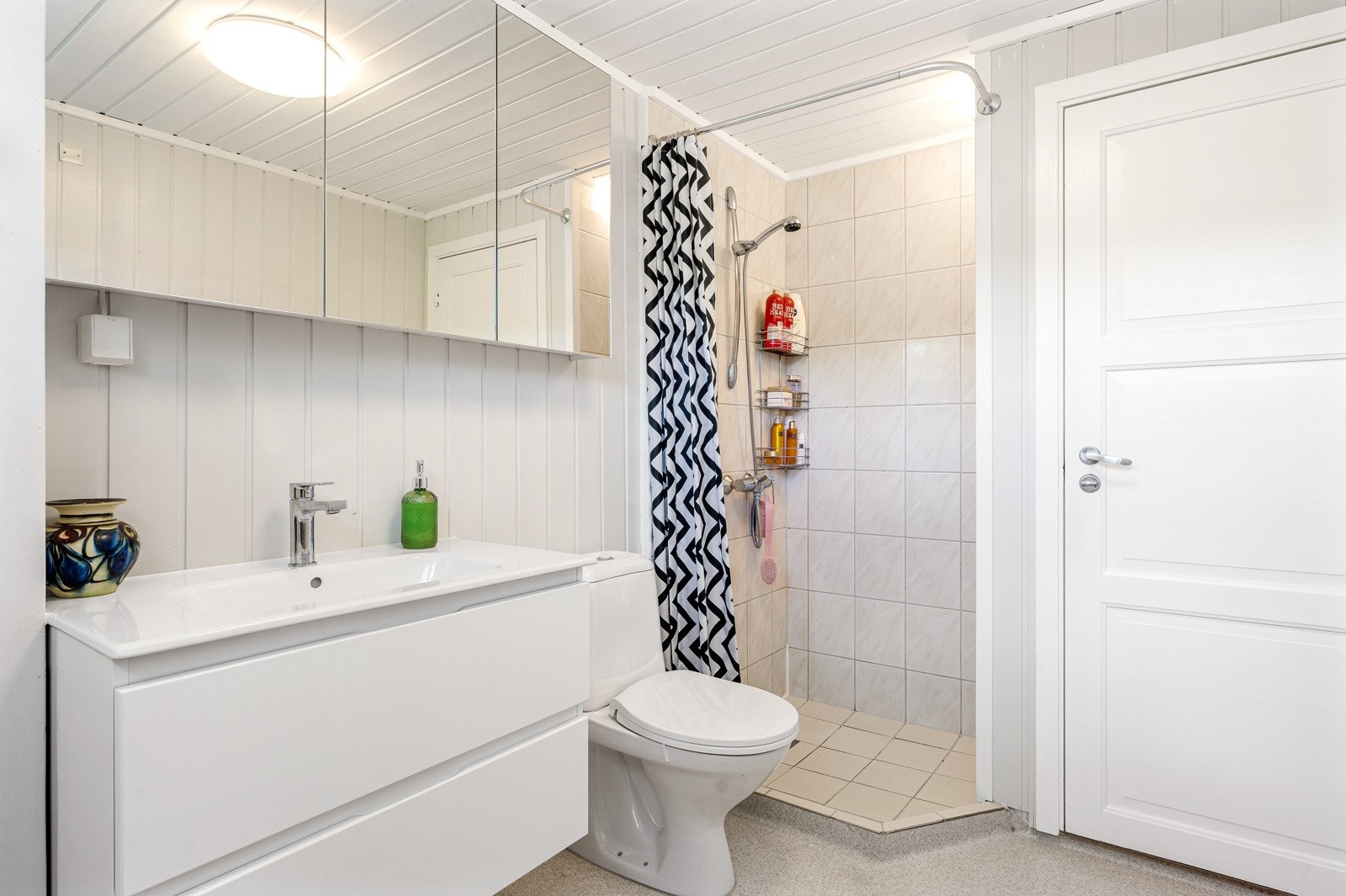 Badet har speilskap med oppbevaring, innredning med skuffer, og hjørnedusj. Galleribilde