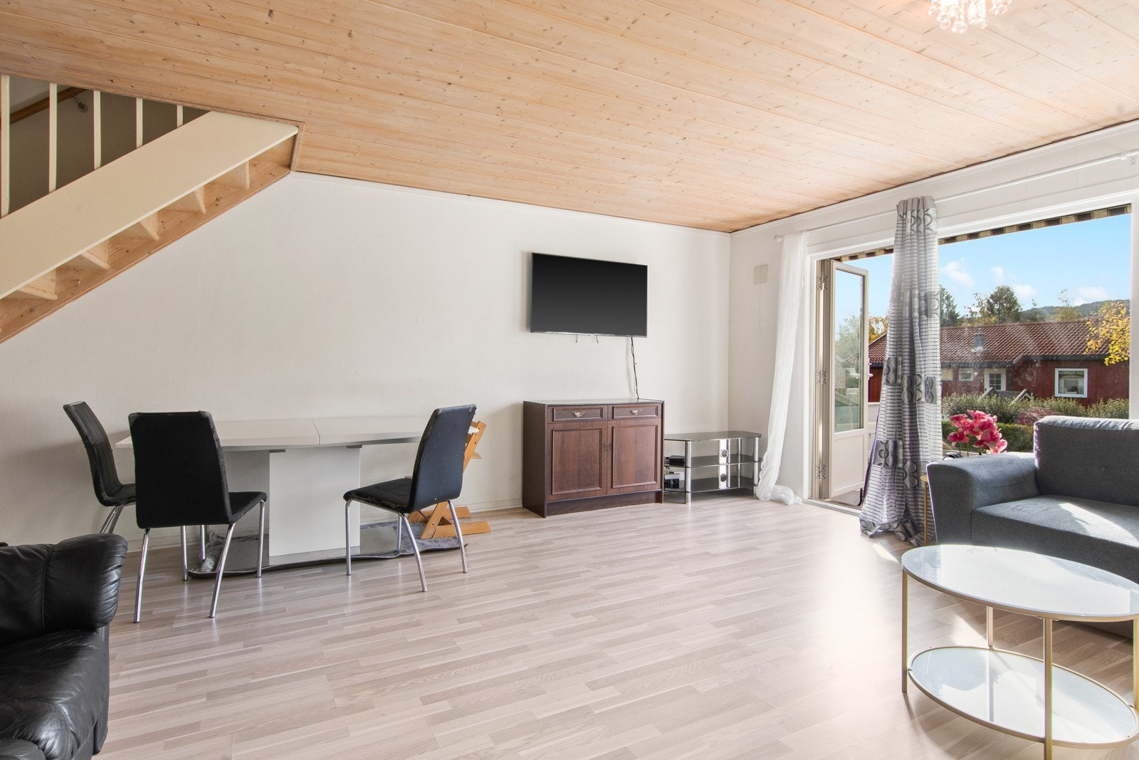 Boligen har en lys stue med plass til sofa, mediemøblement og spisestue Galleribilde