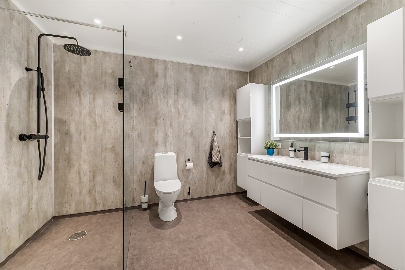 Delikat og tidløst innredet bad med belegg på gulv og baderomsplater på vegg. Rommet er innredet med baderomsinnredning, toalett og dusj med glassvegg. Galleribilde