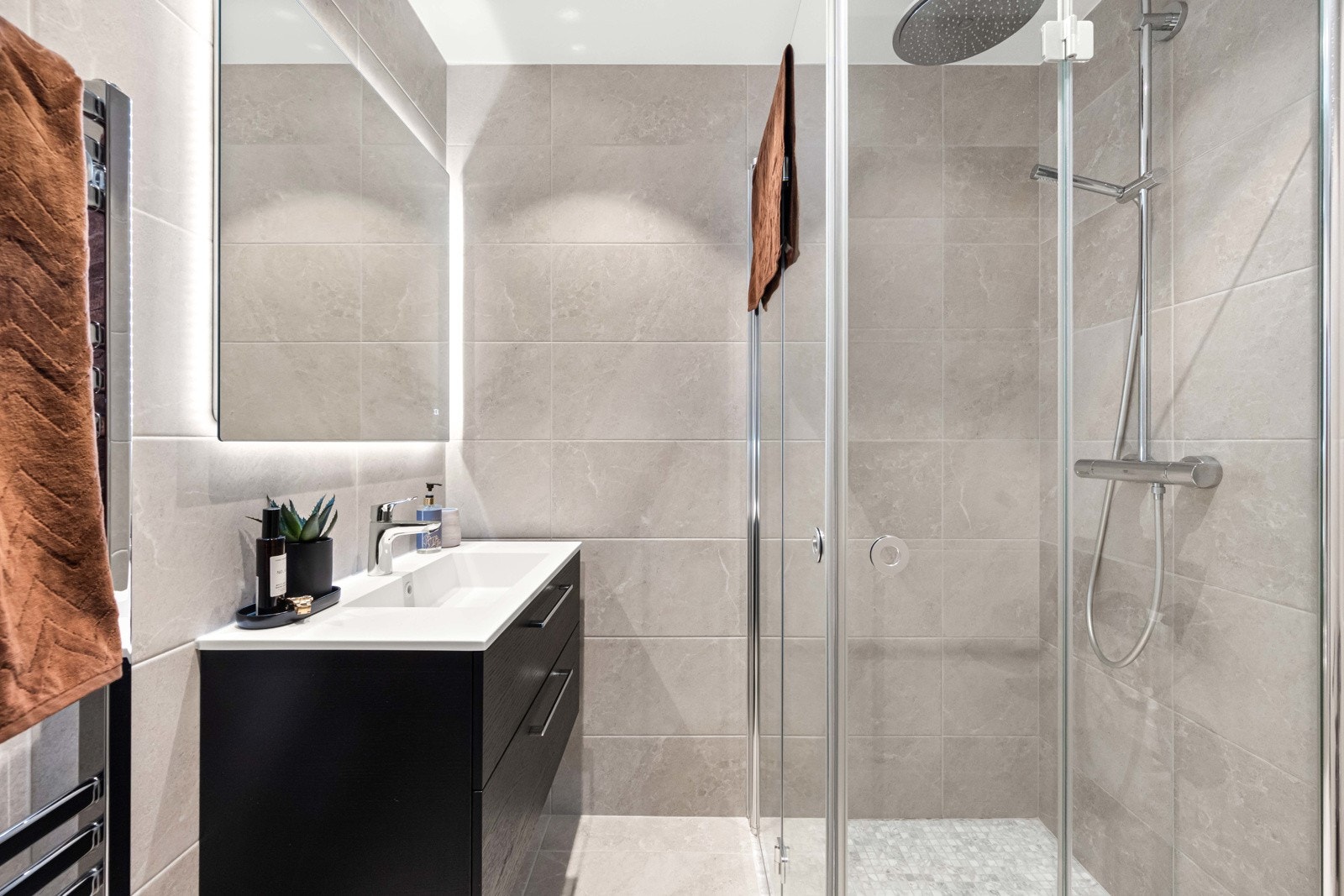 Boligen inneholder et pent flislagt baderom fra 2017 med varmekabler i gulv og downlights i himling. Badet er utstyrt med vegghengt servantinnredning med skuffer og det er speil med belysning over servanten fra 2022 Galleribilde