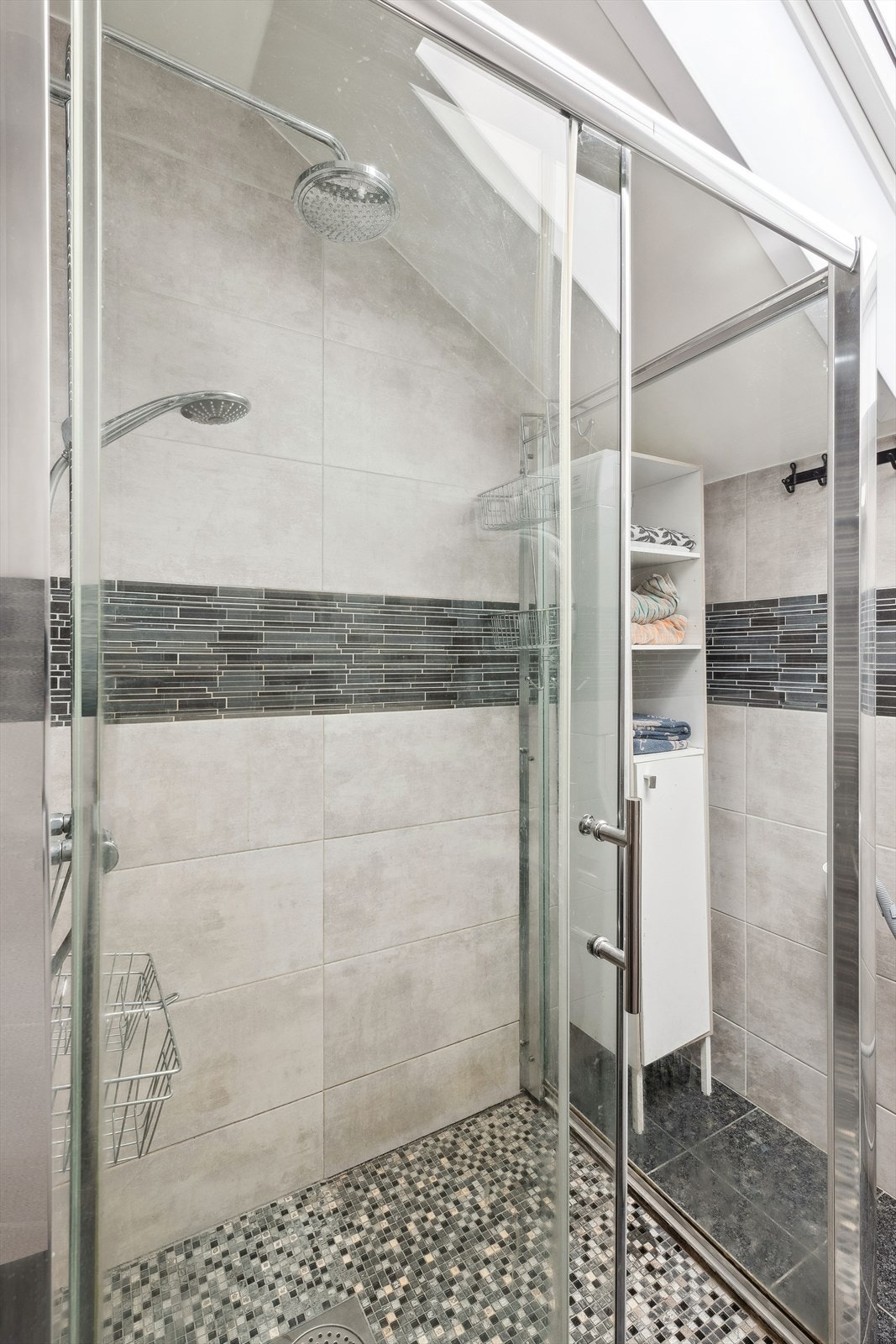 Badet er utstyrt med dusjnisje med glassdør, vegghengt wc og romslig servantinnredning med skuffer, side- og overskap Galleribilde