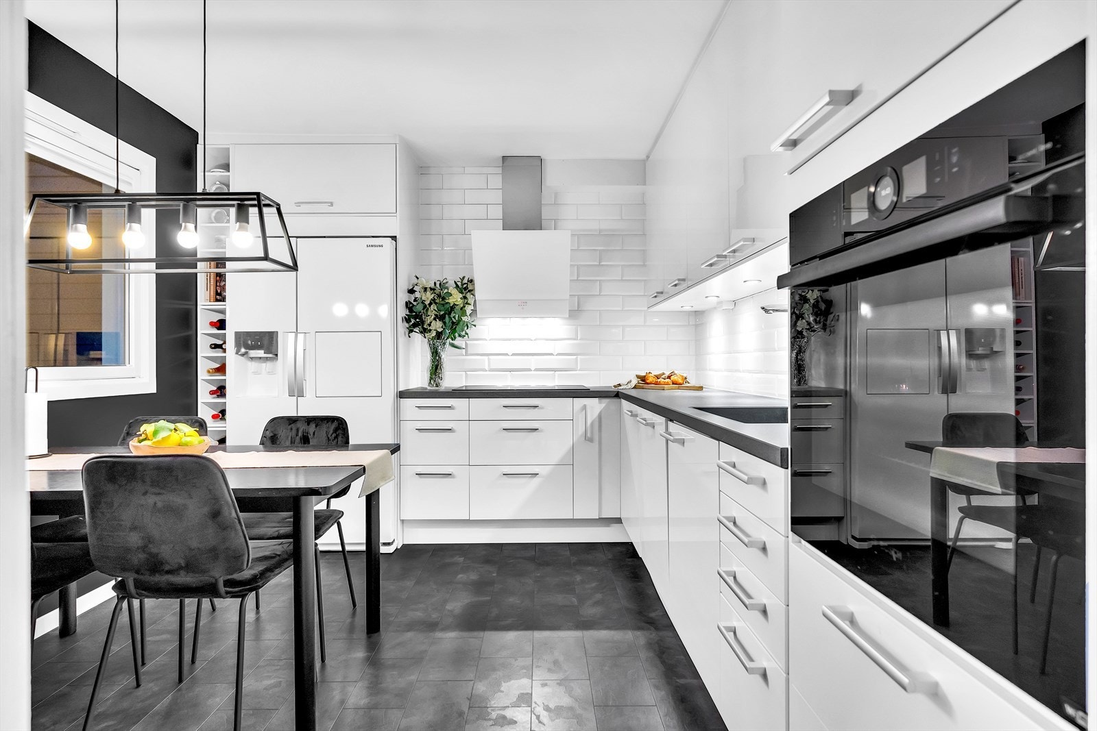 Epoc kjøkken med integrert ovn, oppvaskmaskin og platetopp med boosterfunksjon. Hvite høyglans skuff- og skapfronter, flislagt vegg med hvite metro-fliser, ovnsvifte med utlufting over tak. Galleribilde