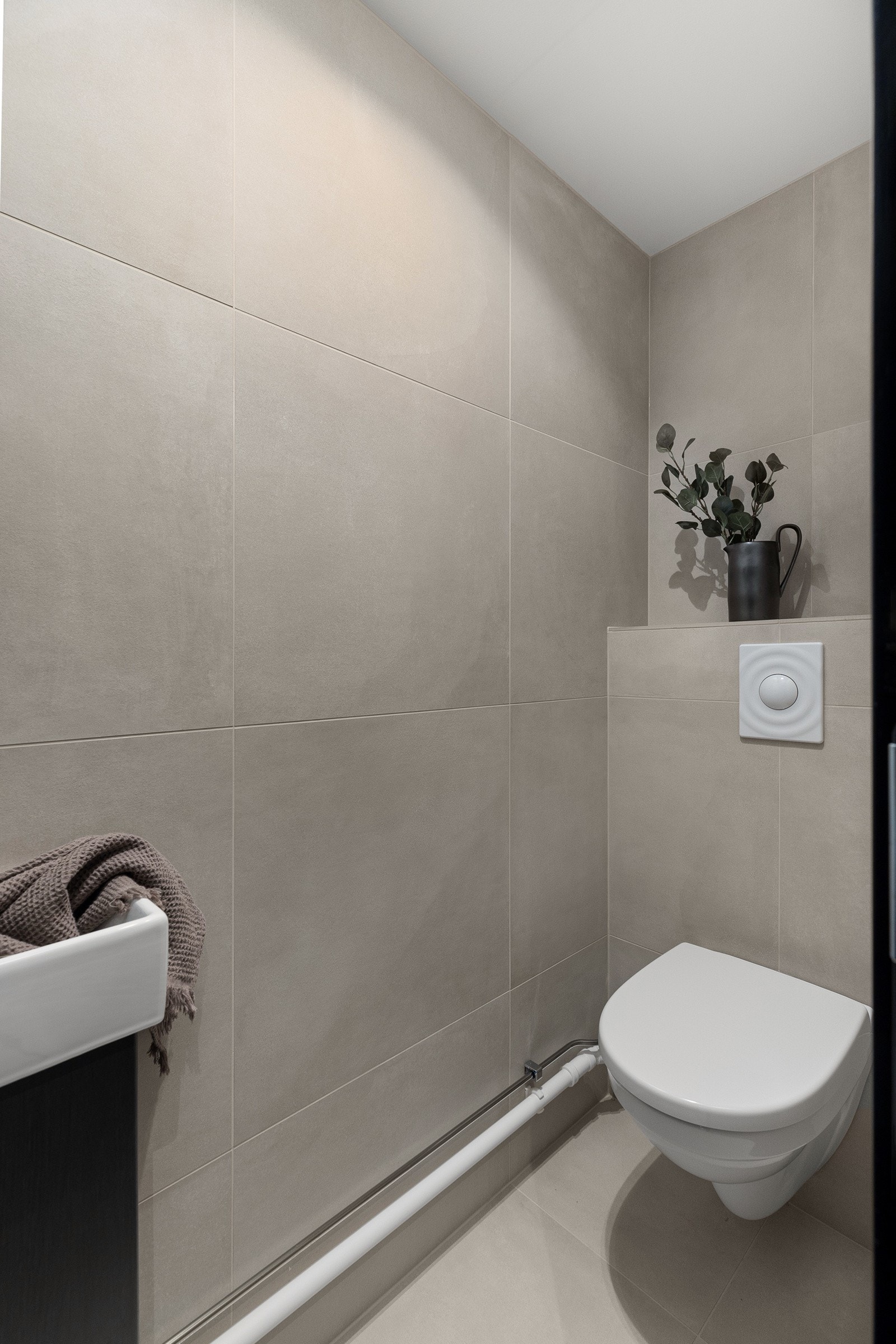 I tilknytning til entréen er det et pent og praktisk flislagt toalettrom med servant og vegghengt toalett Galleribilde