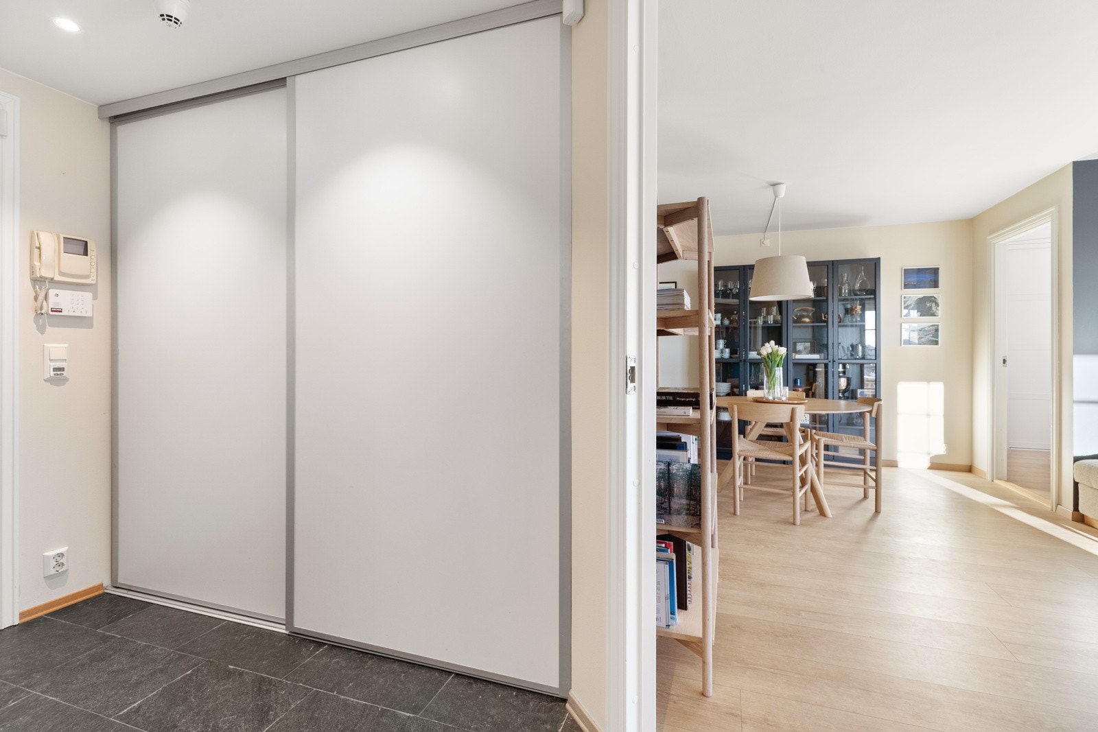 Hyggelig og imøtekommende entré med flere praktiske oppbevaringsmuligheter i stor skyvedørsgarderobe og vegghengt hylle Galleribilde