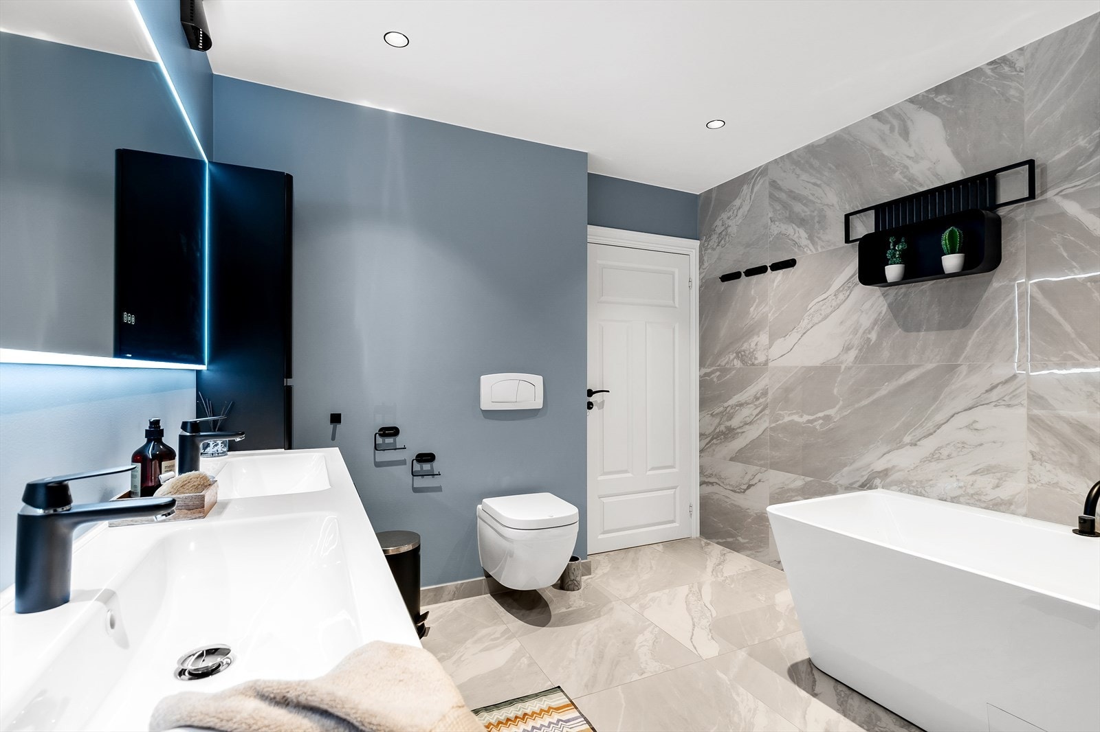 Hovedleiligheten/Leilighet 1: Badet har både flislagte gulv og delvis flislagte vegger. Ett par vegger er malt i en lekker og tidsriktig blåfarge. Galleribilde