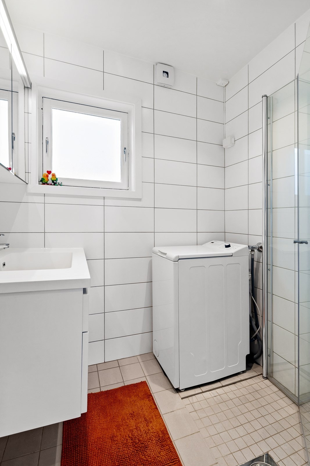 Leilighet 3: Flislagt baderom fra 2014 innredet med heldekkende servant på innredning, overhengende speil og dusjnisje. Plass for vaskemaskin Galleribilde