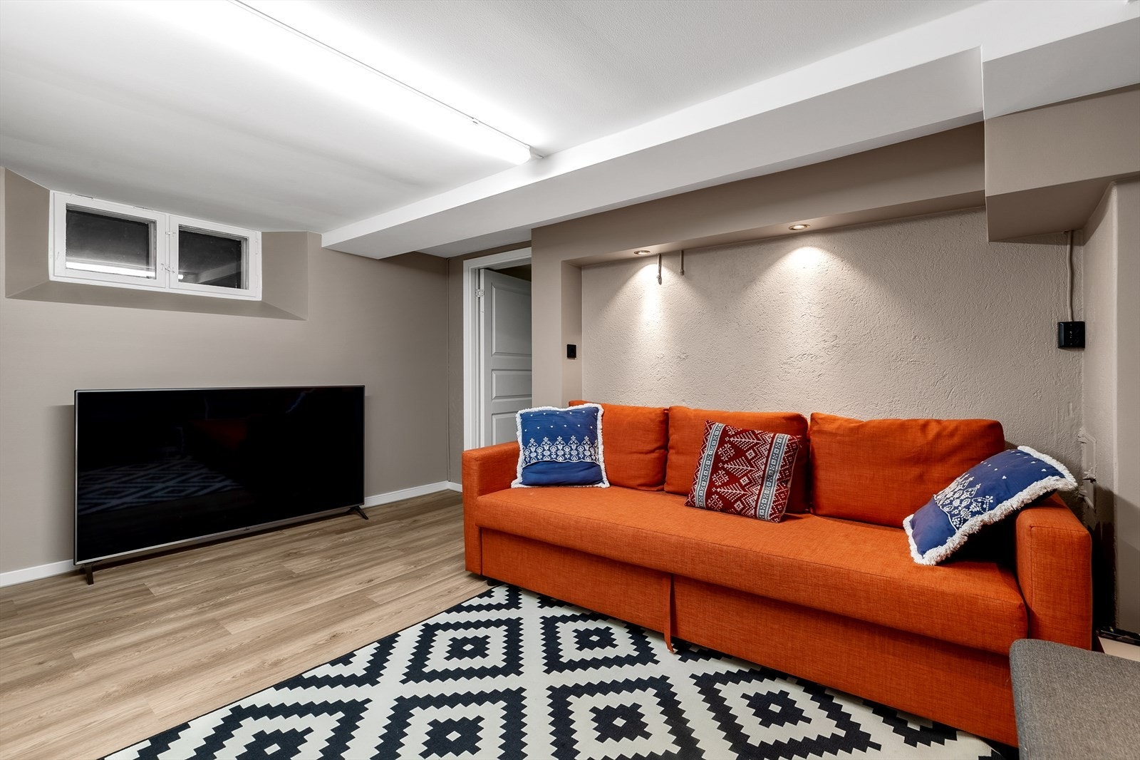 Hovedleilighet/Leilighet 1: Kjellerstue med fin plass for sofa, tv-møblement m.m. I byggetegningene fra kommunen er dette et vaskerom. Galleribilde