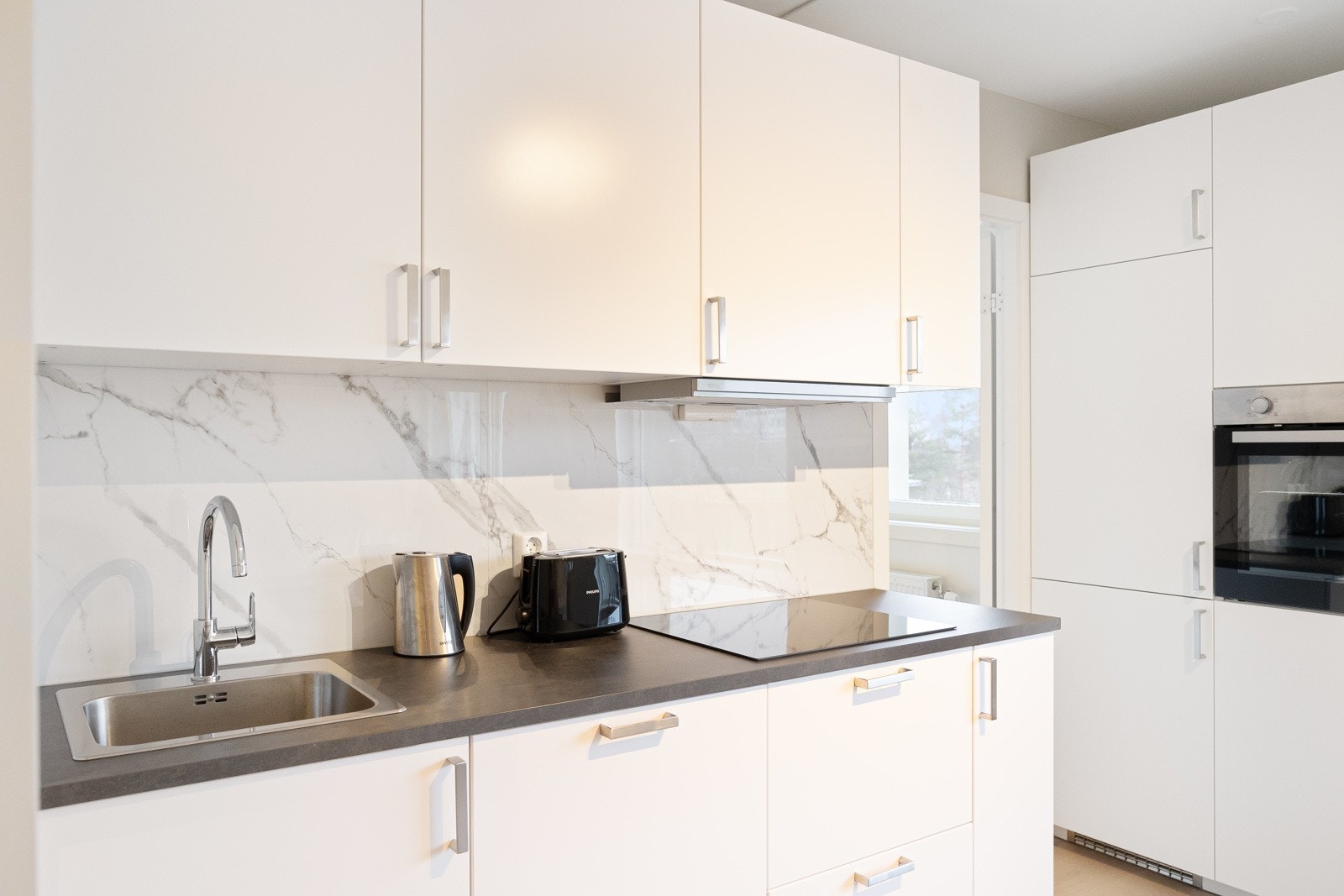 Nedfelt oppvaskkum i rustfritt stål og ventilator over kokesone. Galleribilde