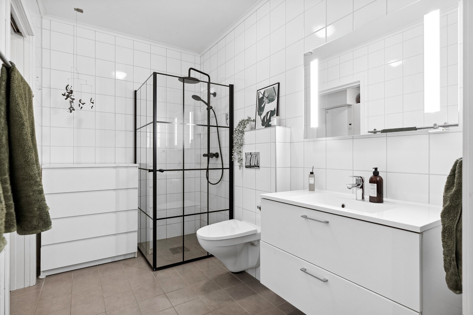 Baderommet ligger i første etasje og er stilrent innredet med skuffeseksjon, speil, vegghengt toalett og regndusj. Galleribilde