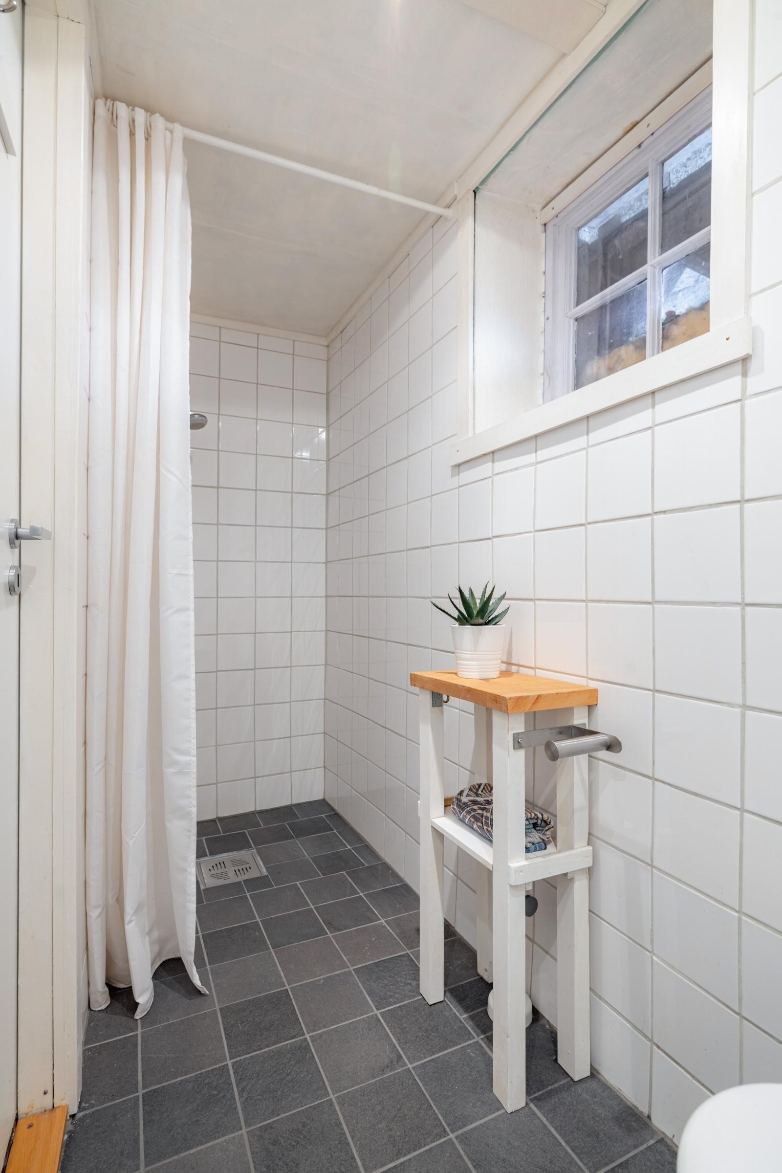 Bad i kjeller er utstyrt med dusj, servant og gulvstående klosett. Det er fliser på vegger og gulv med varmekabler. Benkeskap og veggskap med profilerte fronter. Galleribilde