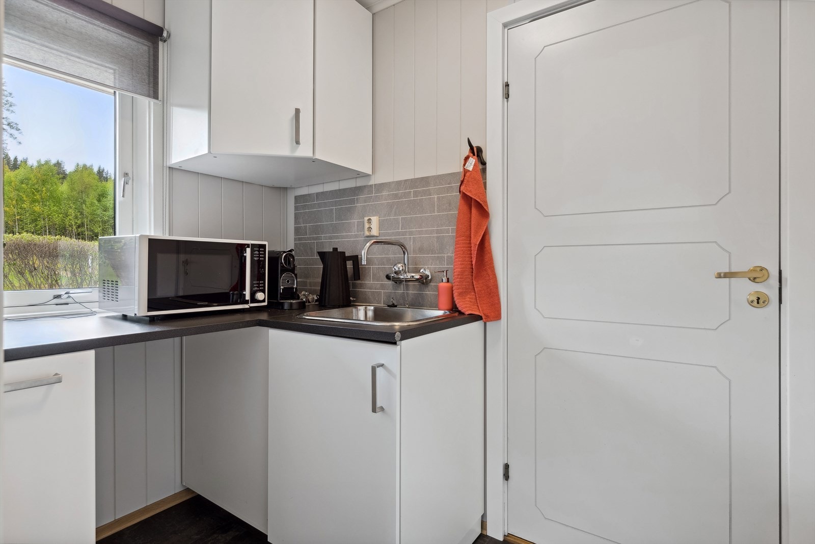 Et lite grovkjøkken ligger ved siden av kjøkkenet. Vinkelinnredning med folierte fronter og skrog. Benkeplate av laminat med nedfelt kum. Galleribilde