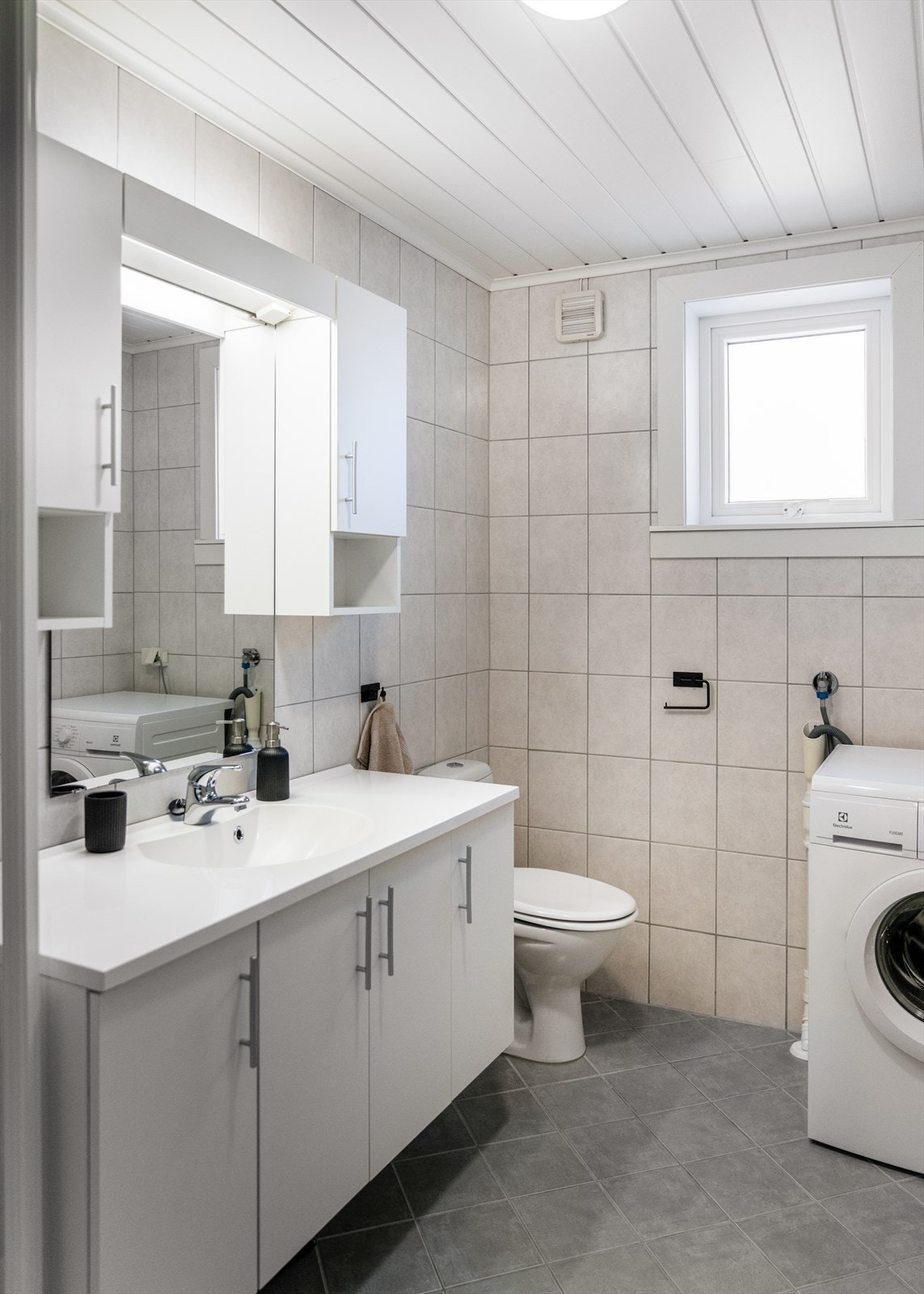 Badet er også innredet med dusjkabinett med praktiske hyller, toalett og opplegg for vaskemaskin. Galleribilde