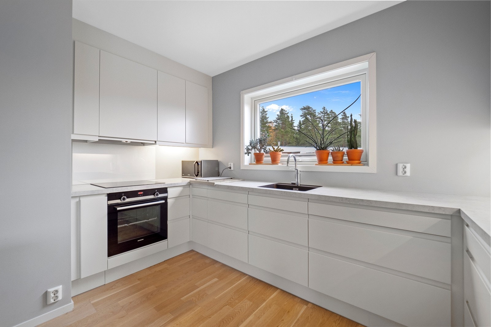 Det er grå benkeplater i laminat med underlimt kum av kunstkompositt med ettgreps blandebatteri. Galleribilde