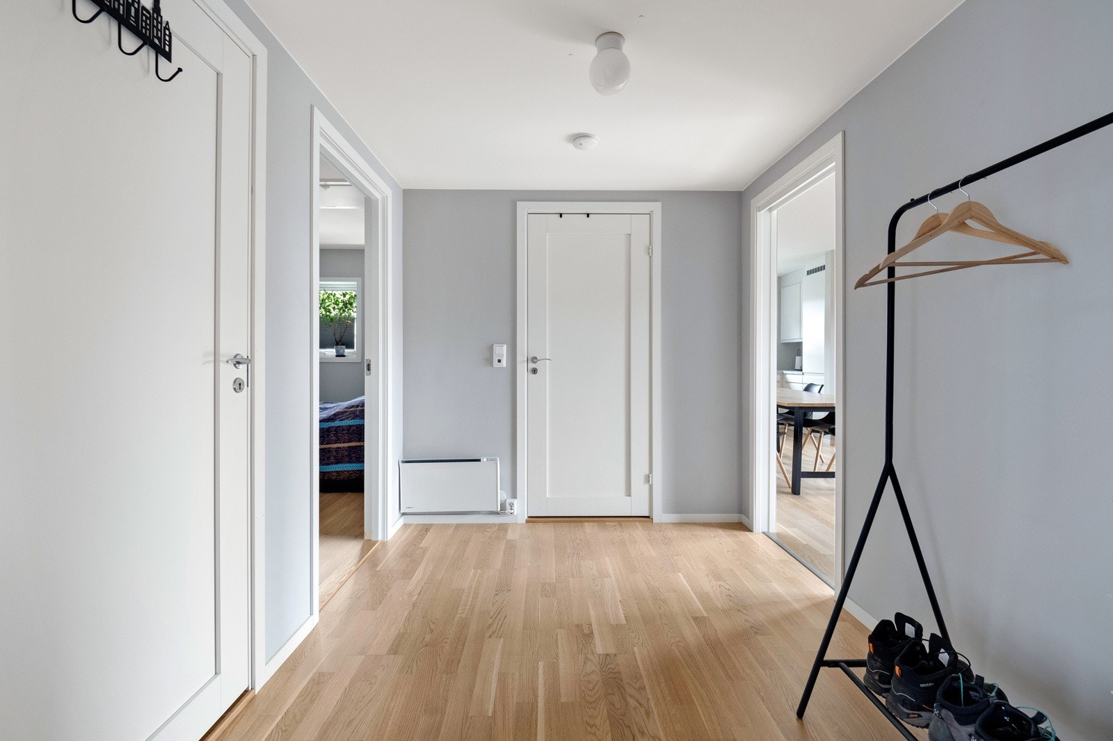 Gjennom et overbygget inngangsparti møter den innbydende entreen deg med god plass for skap, kommoder eller lignende, og delikat parkett på gulv med slette vegger malt i lys grå fargetone. Galleribilde