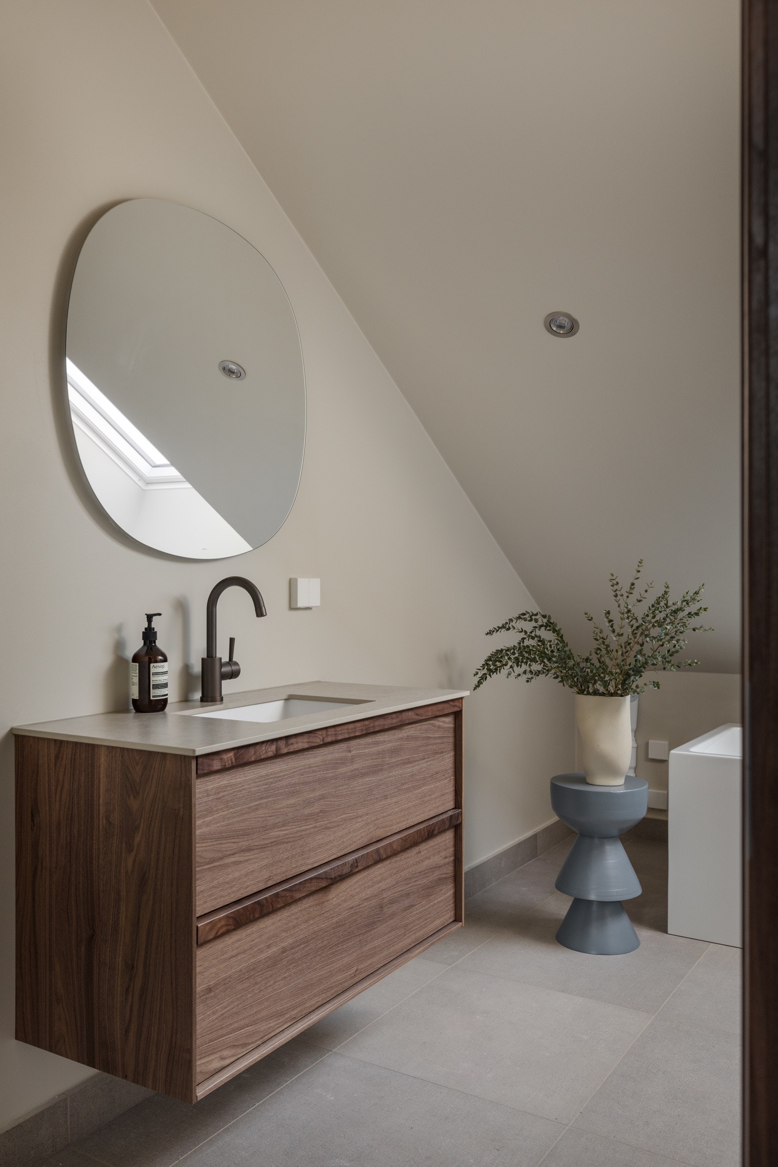 Lekkert baderom som inneholder bl.a badekar, servantskap med glatte, folierte fronter, nedfelt servant og veggmontert toalett. Galleribilde