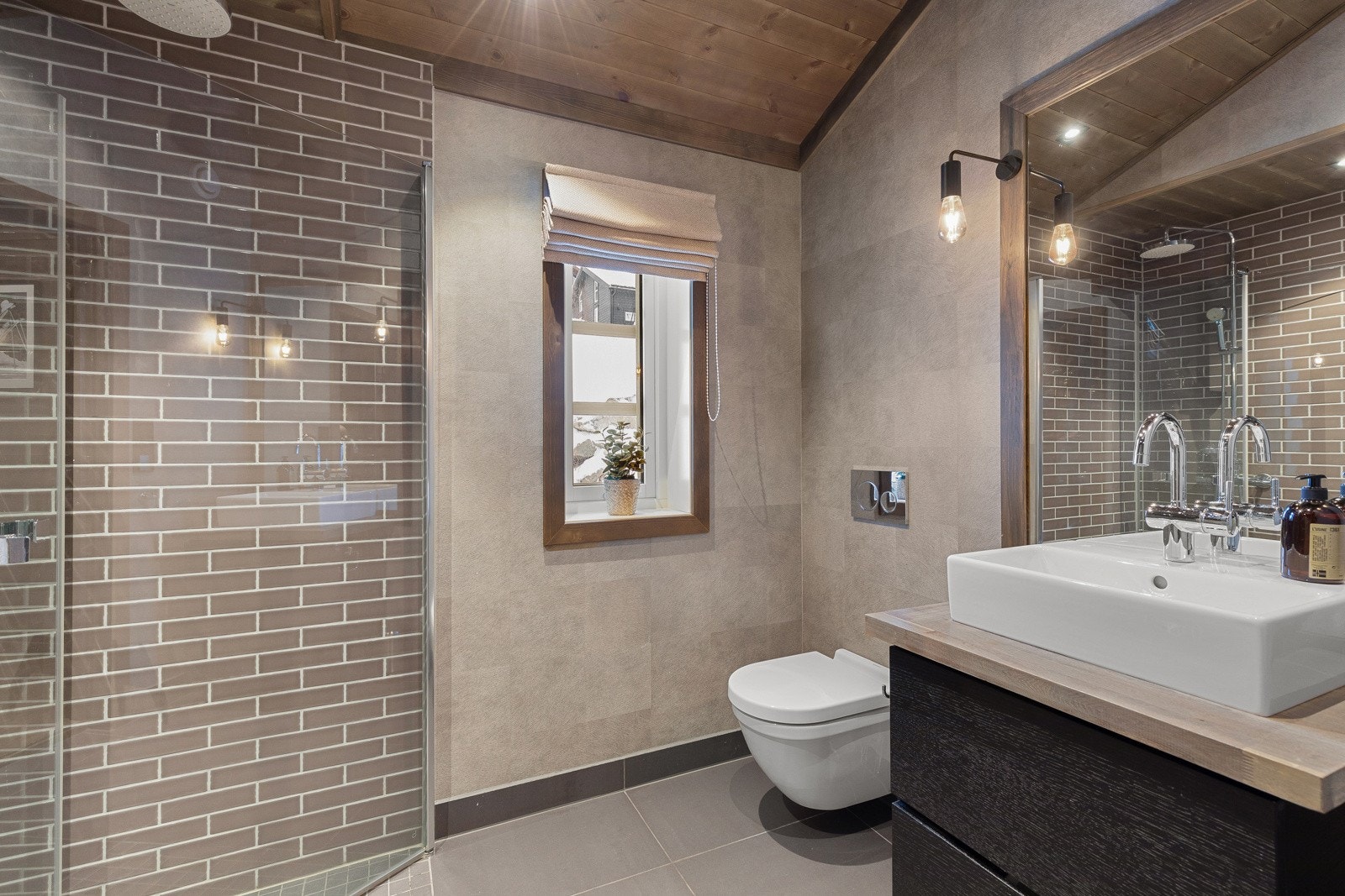 Badet har flisar på golv og delar av vegg, samt vinylbelegg på resten. Himling av panel med spotbelysning. Galleribilde