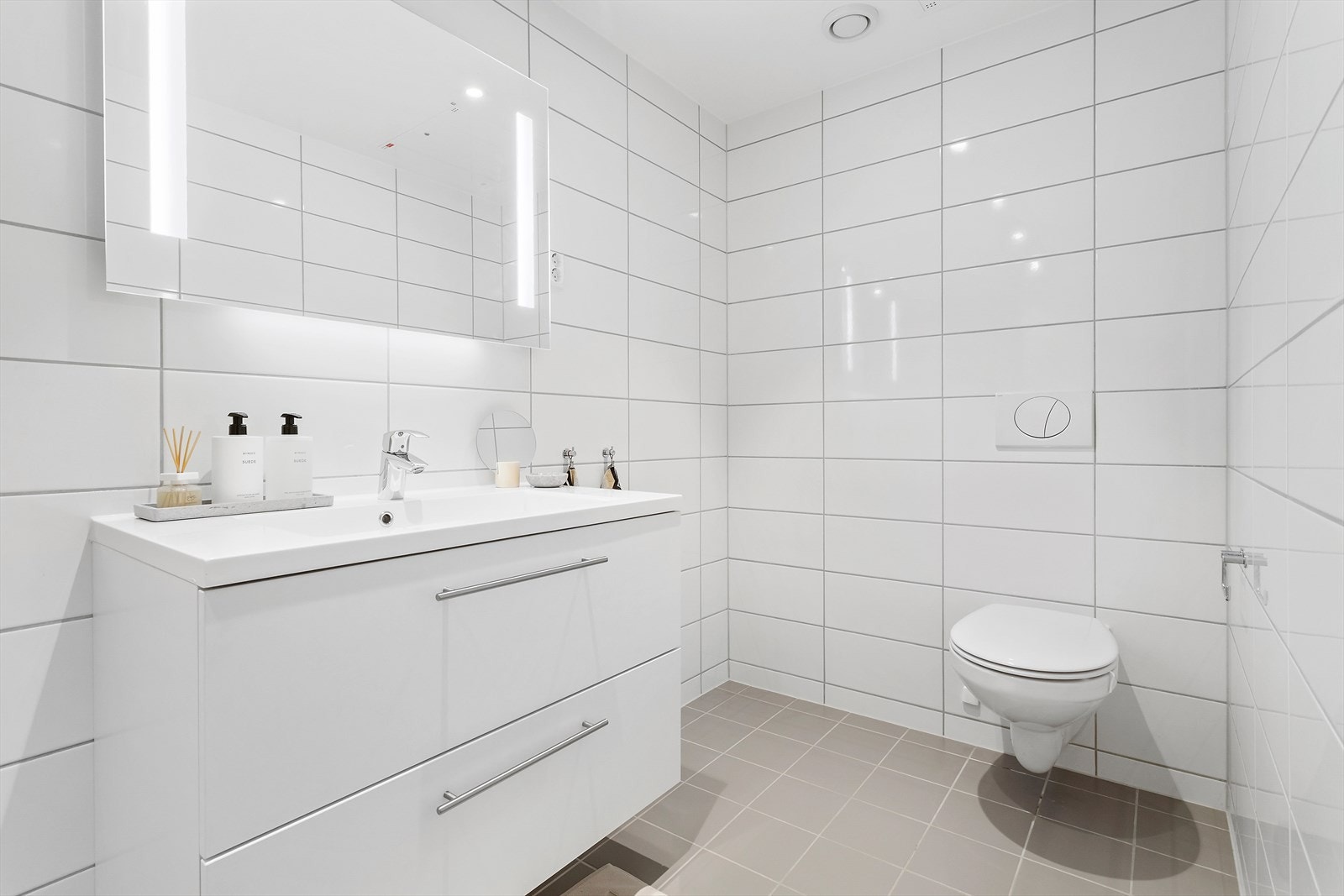 - Badet er innredet med hvit servantinnredning med heldekkende servanttopp, speil med tilhørende belysning, vegghengt toalett og dusjhjørne med dusjopplegg på vegg og innfellbare dører i glassutførelse - Galleribilde