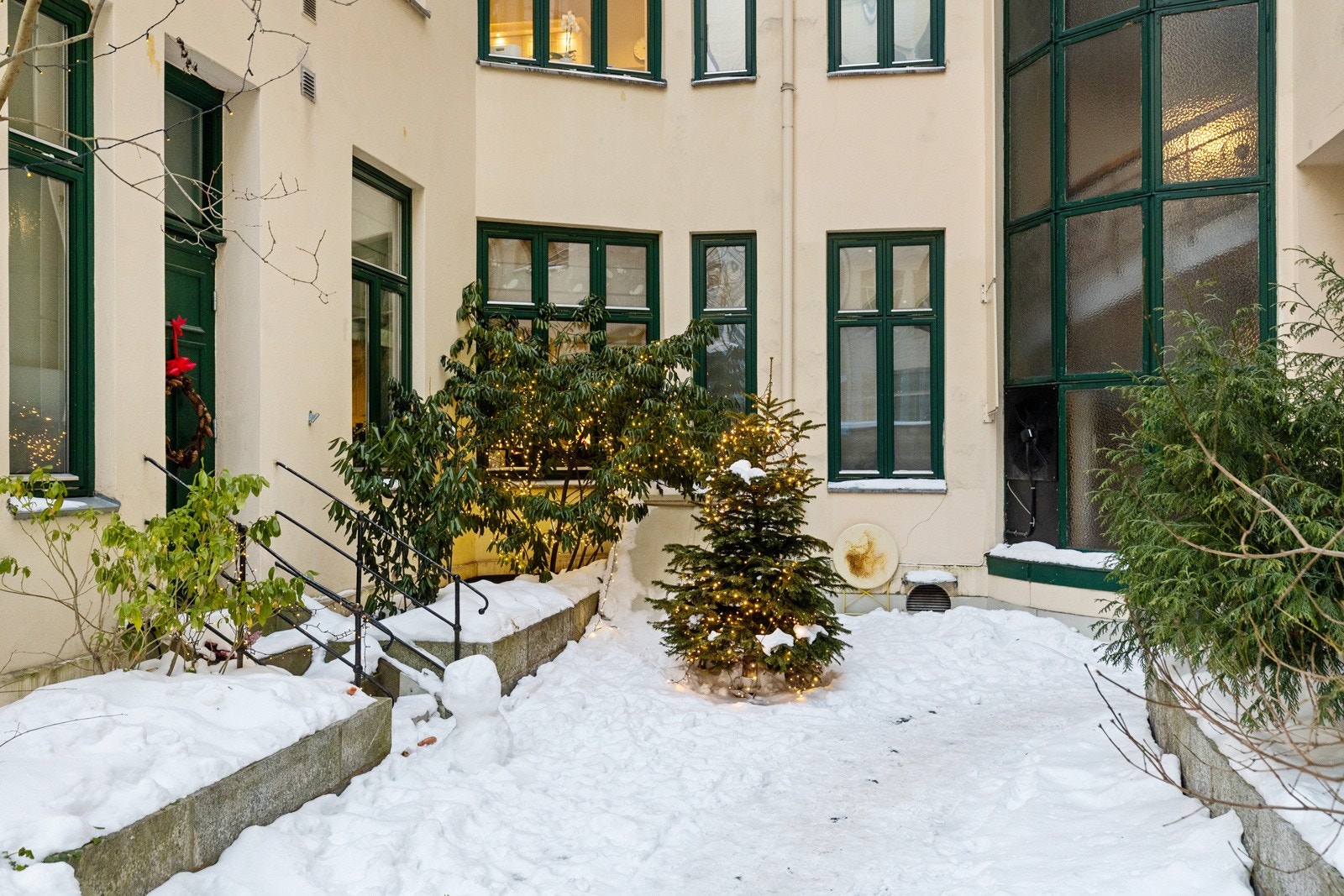 Frodig bakgård med trær, blomster og sittegrupper Galleribilde