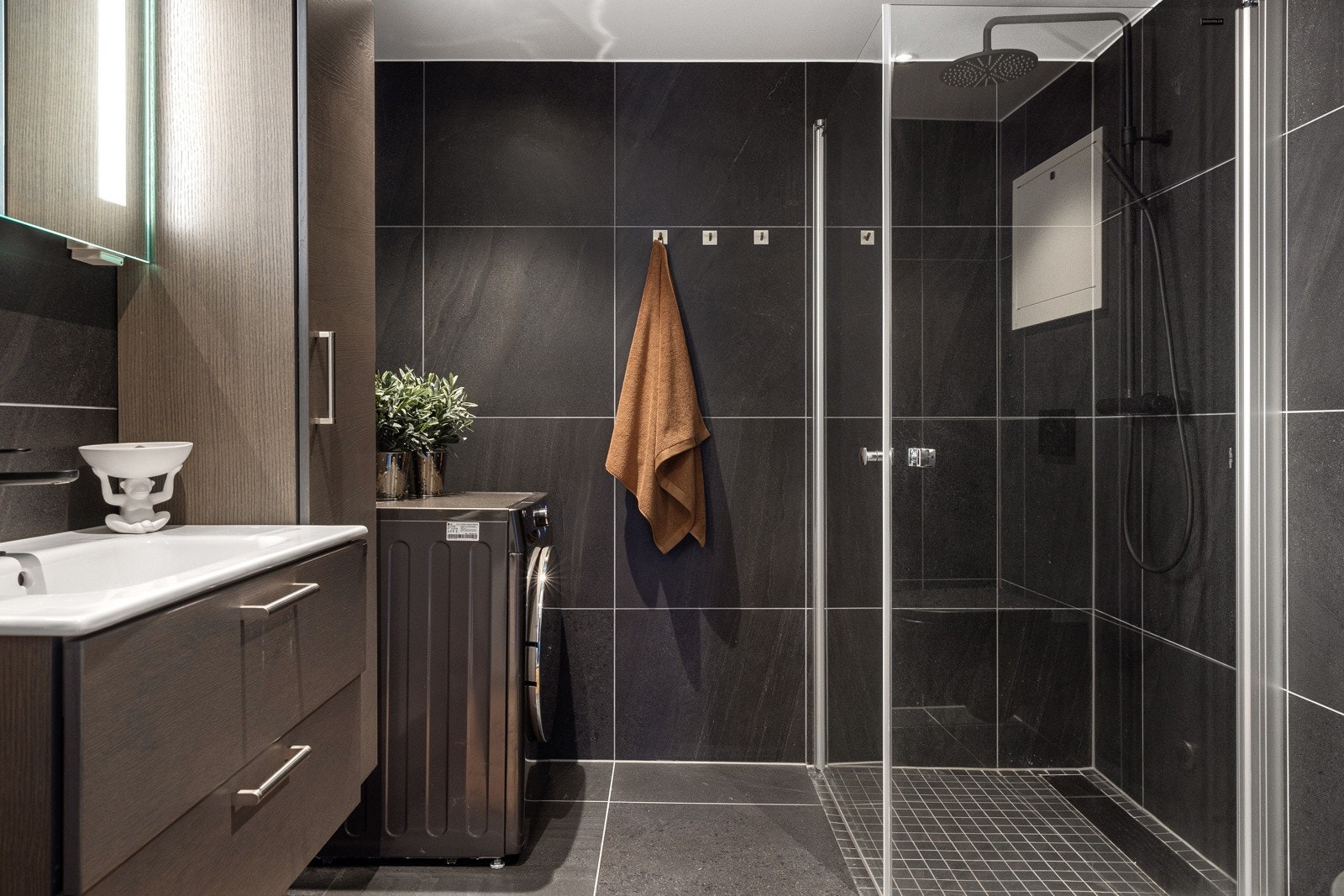 Baderomsinnredning med heldekkende servant, høyskap og speil med belysning. Galleribilde