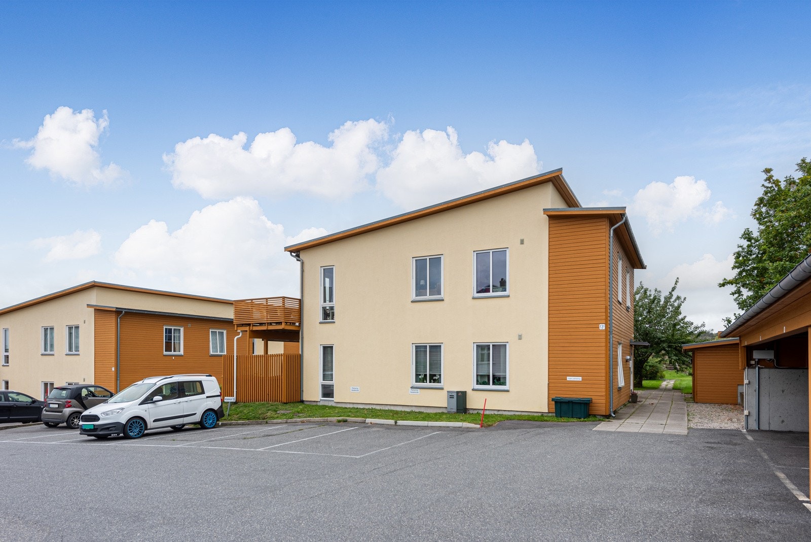 Carport til høyre i bilde, parkeringsplassen til leiligheten er nærmest boligen. Asfaltert gårdsplass og gjesteparkering rett utenfor bygningen. Galleribilde