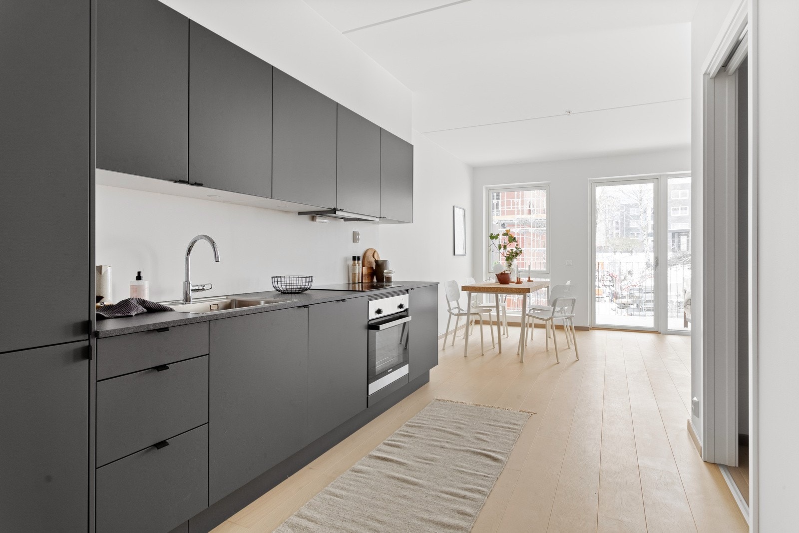 Integrerte hvitevarer som stekeovn, nedfelt induksjonstopp, avtrekksvifte oppvaskmaskin og kjøleskap med frysedel. Galleribilde