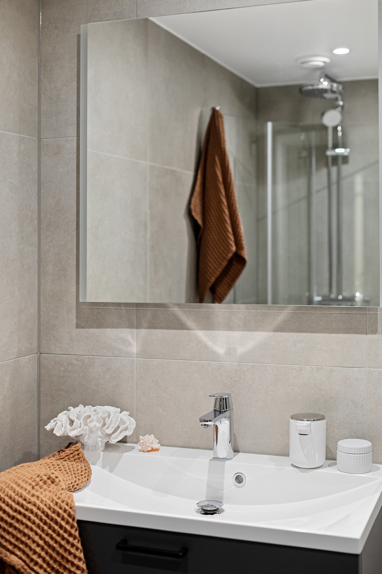 Moderne baderomsinnredning fra Sigdal med skuffer og heldekkende servant, speil med innfelt ledlys over. Galleribilde