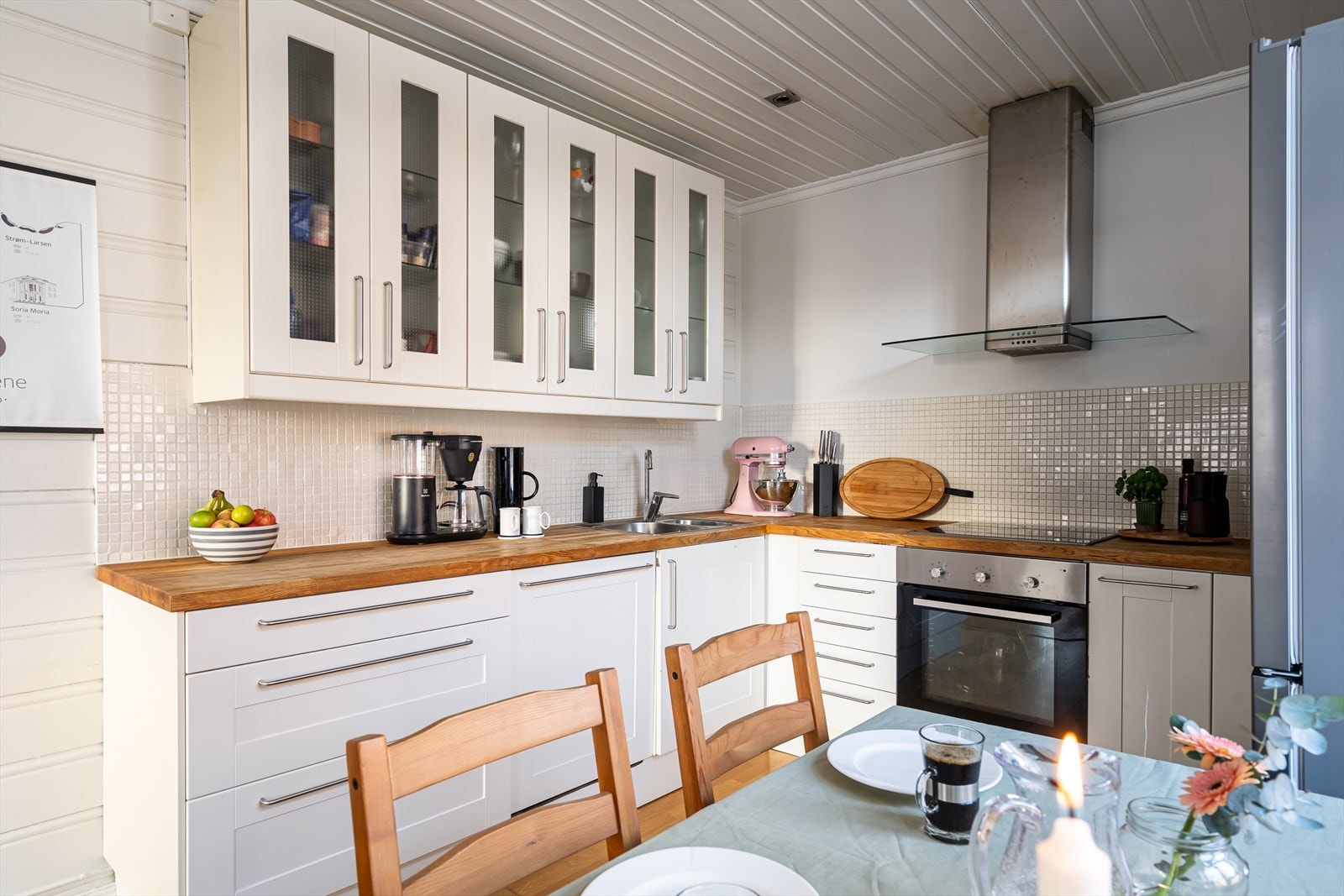 Pent hvitt kjøkken som har godt med oppbevaring og benkplass. Galleribilde