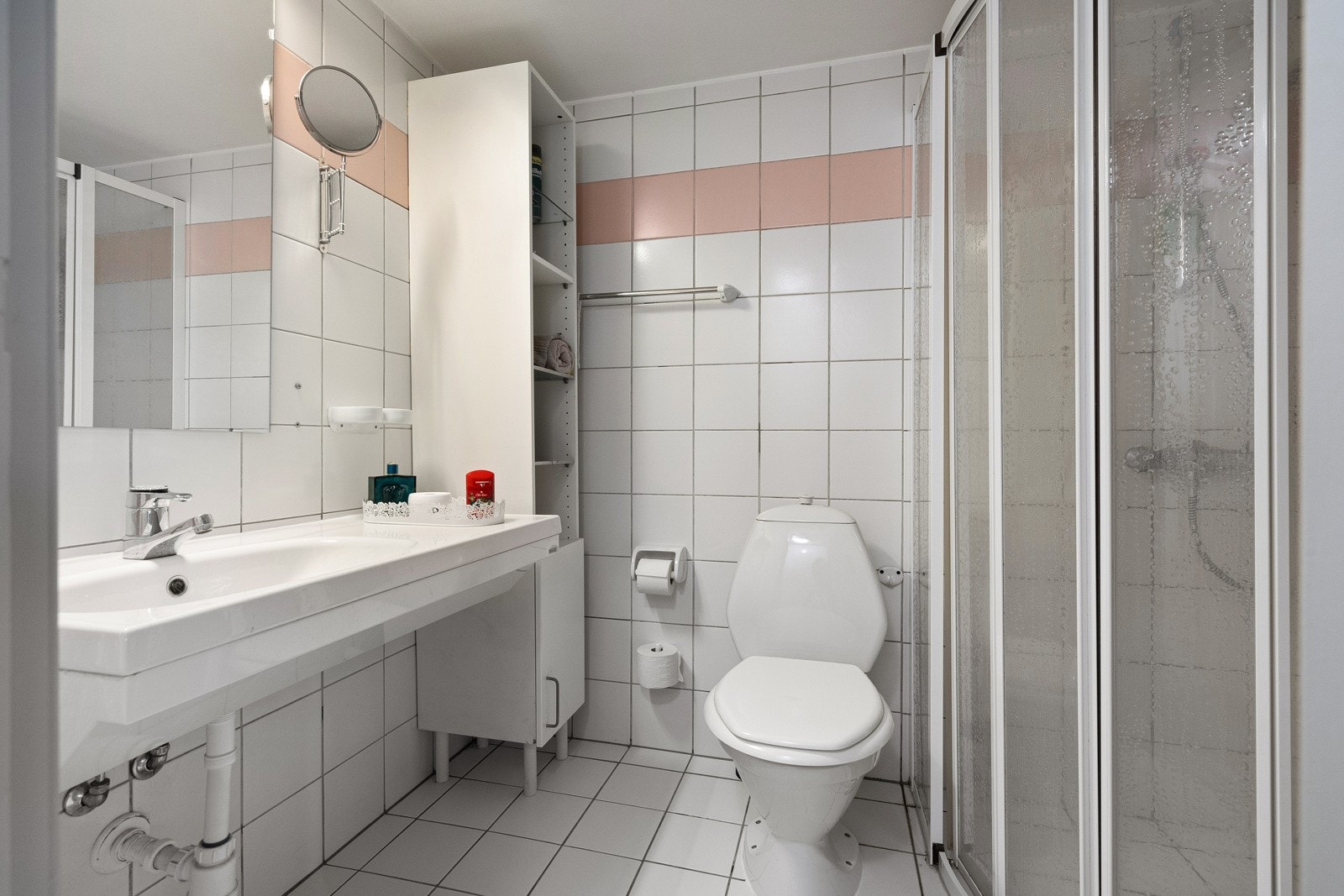 Romslig baderom med dusjhjørne, gulvstående toalett og vegghengt servantinnredning. Galleribilde