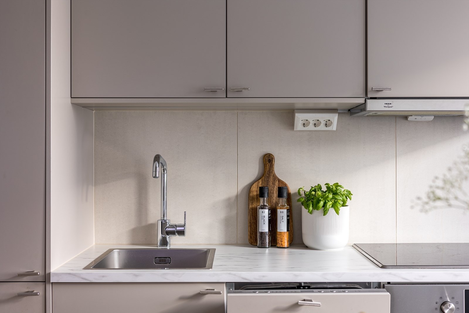 - Kjøkkeninnredning med glatte fronter. Laminat benkeplate med nedfelt vaskekum. Fliser og belysning over benkeplaten. Takhøye overskap - Galleribilde