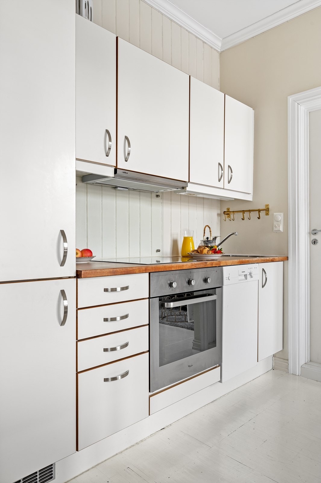 Kjøkkeninnredning med glatte hvite fronter og benkeplate av tre. Galleribilde