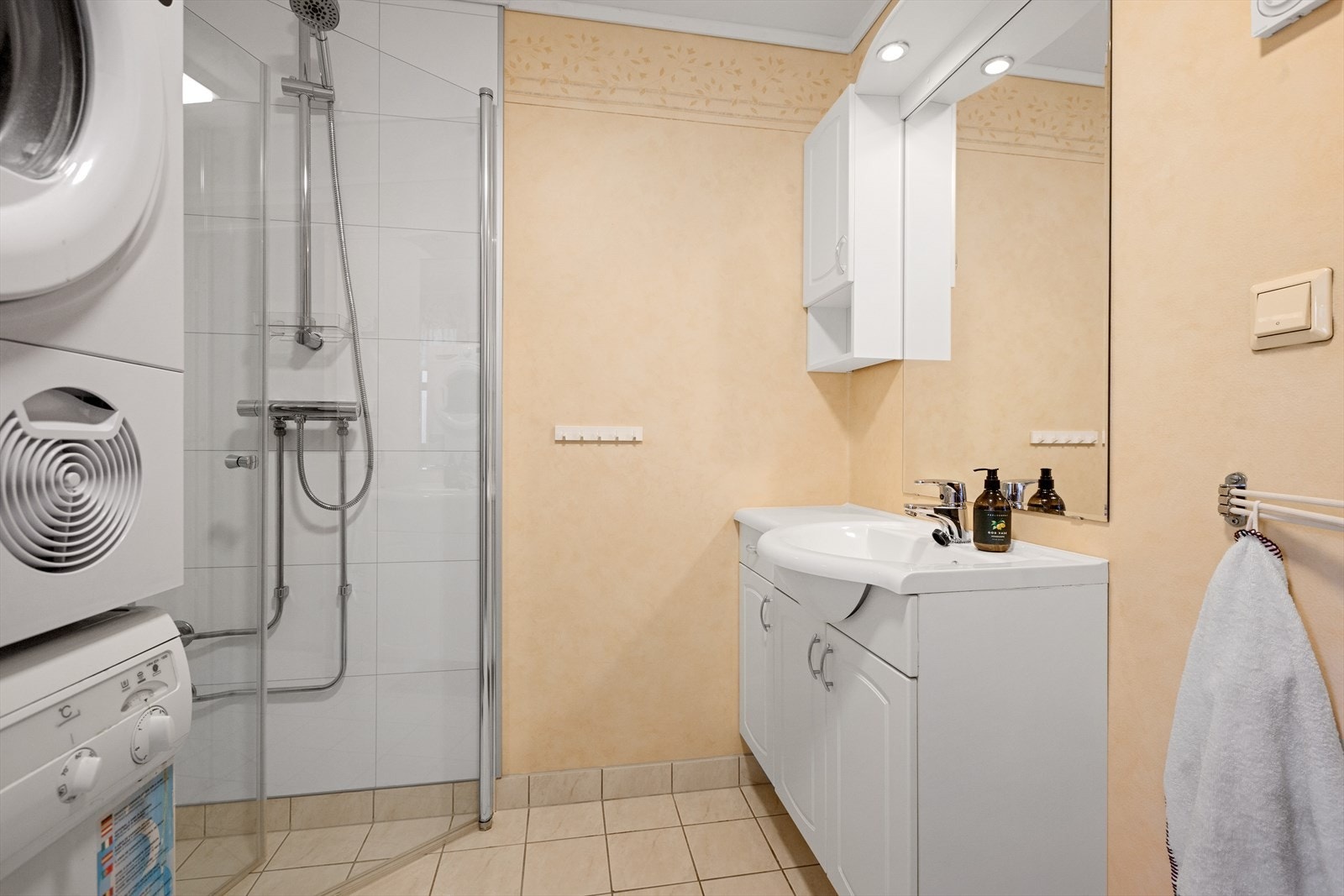 Badet er innredet med hvit innredning med heldekkende servant, veggskap og speil. Dusløsning med glassvegger og toalett. Galleribilde